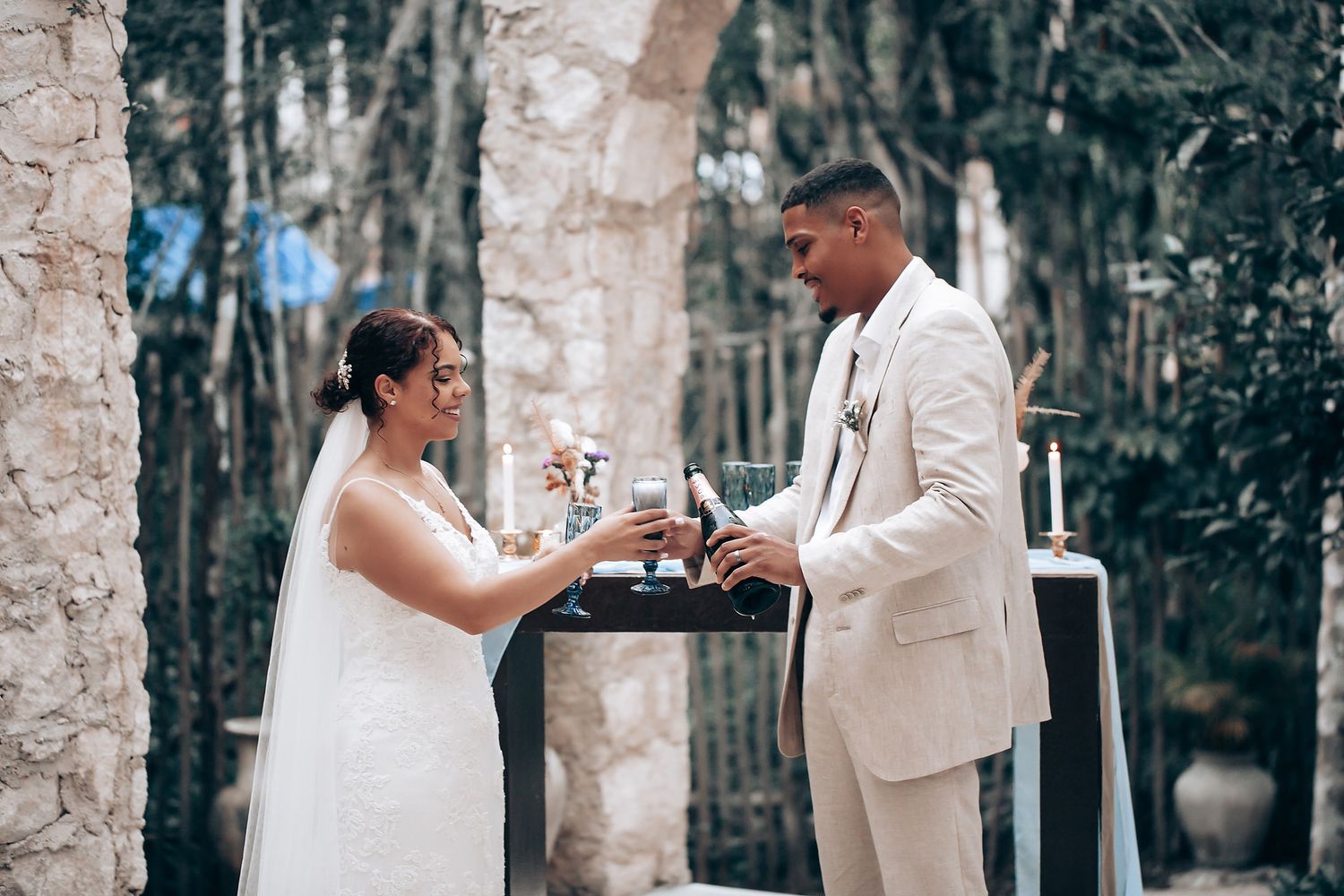 A tender wedding moment photographed against a stone wall backdrop.