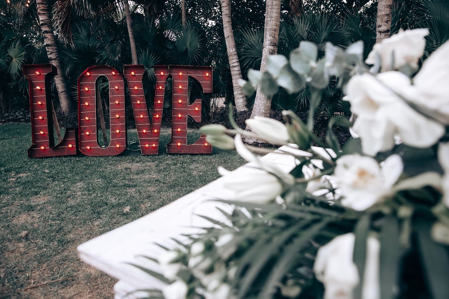 White orchids and tropical greenery decorate an outdoor wedding venue.