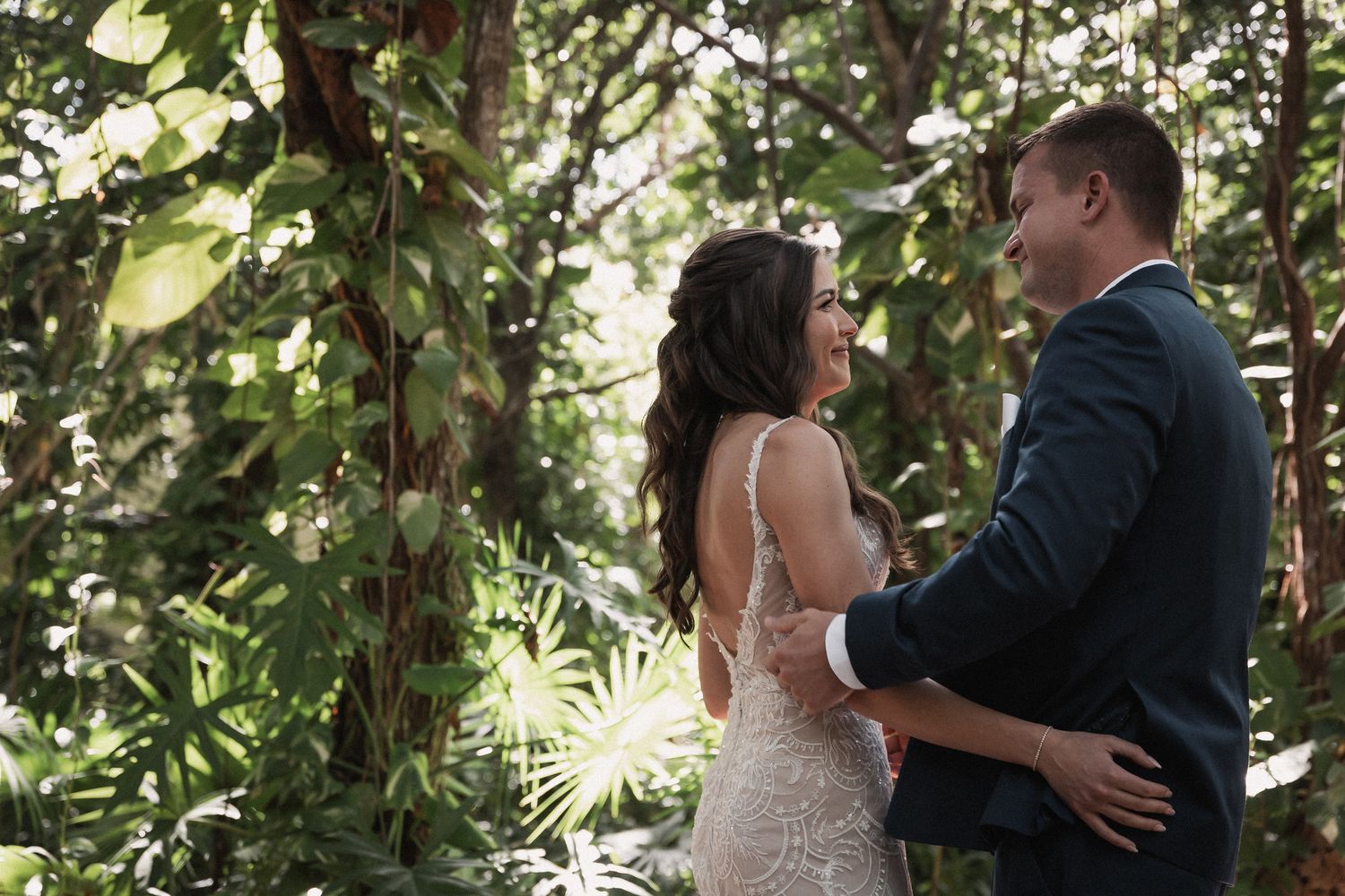 Bride and groom sharing an intimate first look moment surrounded by lush tropical greenery.