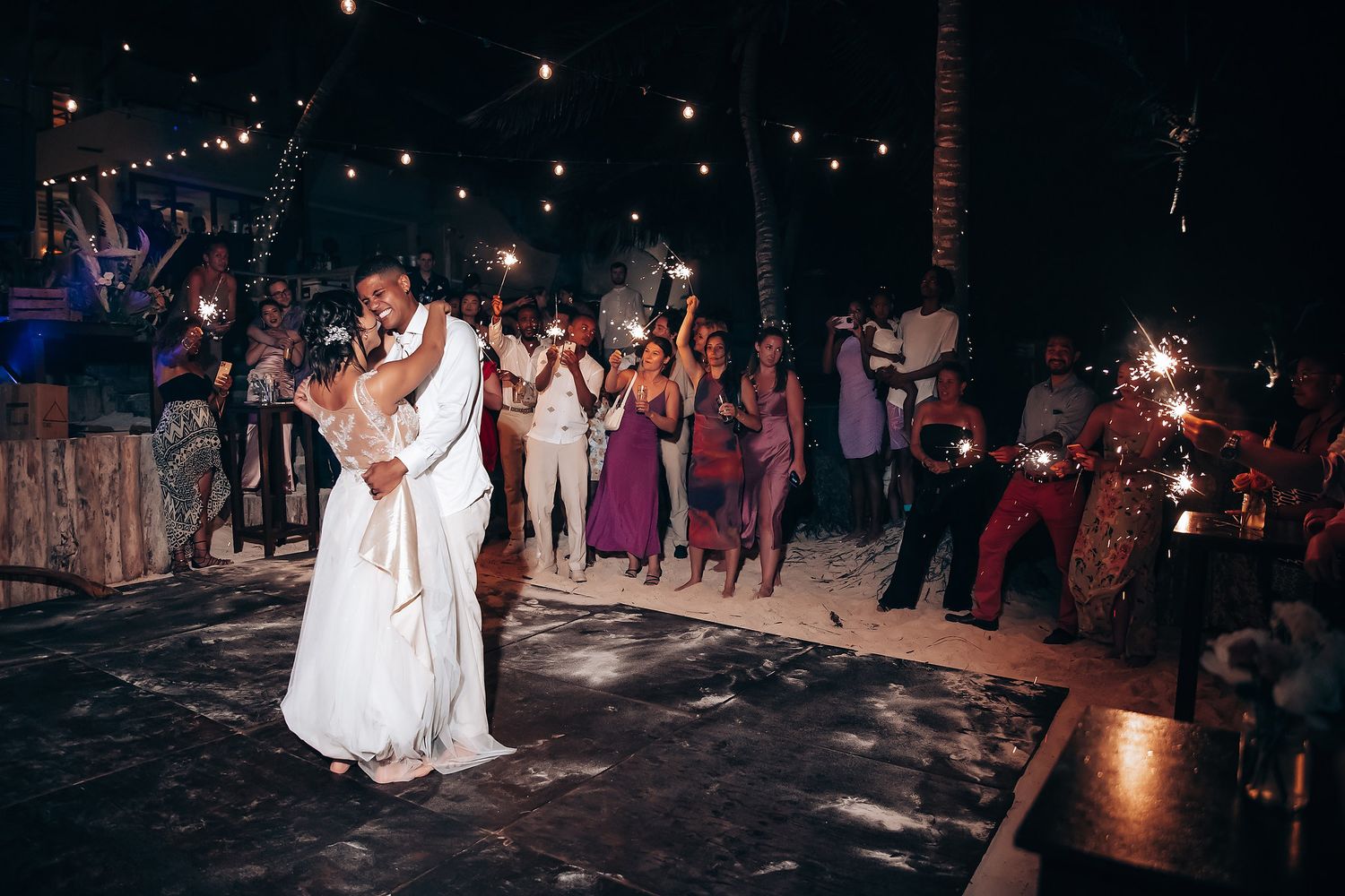 Evening wedding reception with couples dancing under twinkling lights.