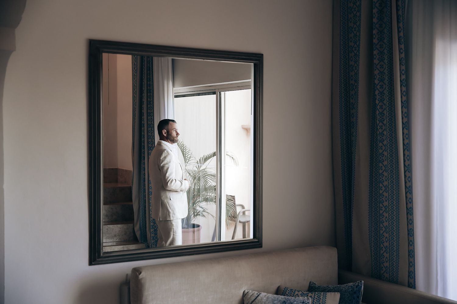 A woman in a white robe stands in front of a mirror, looking at herself.