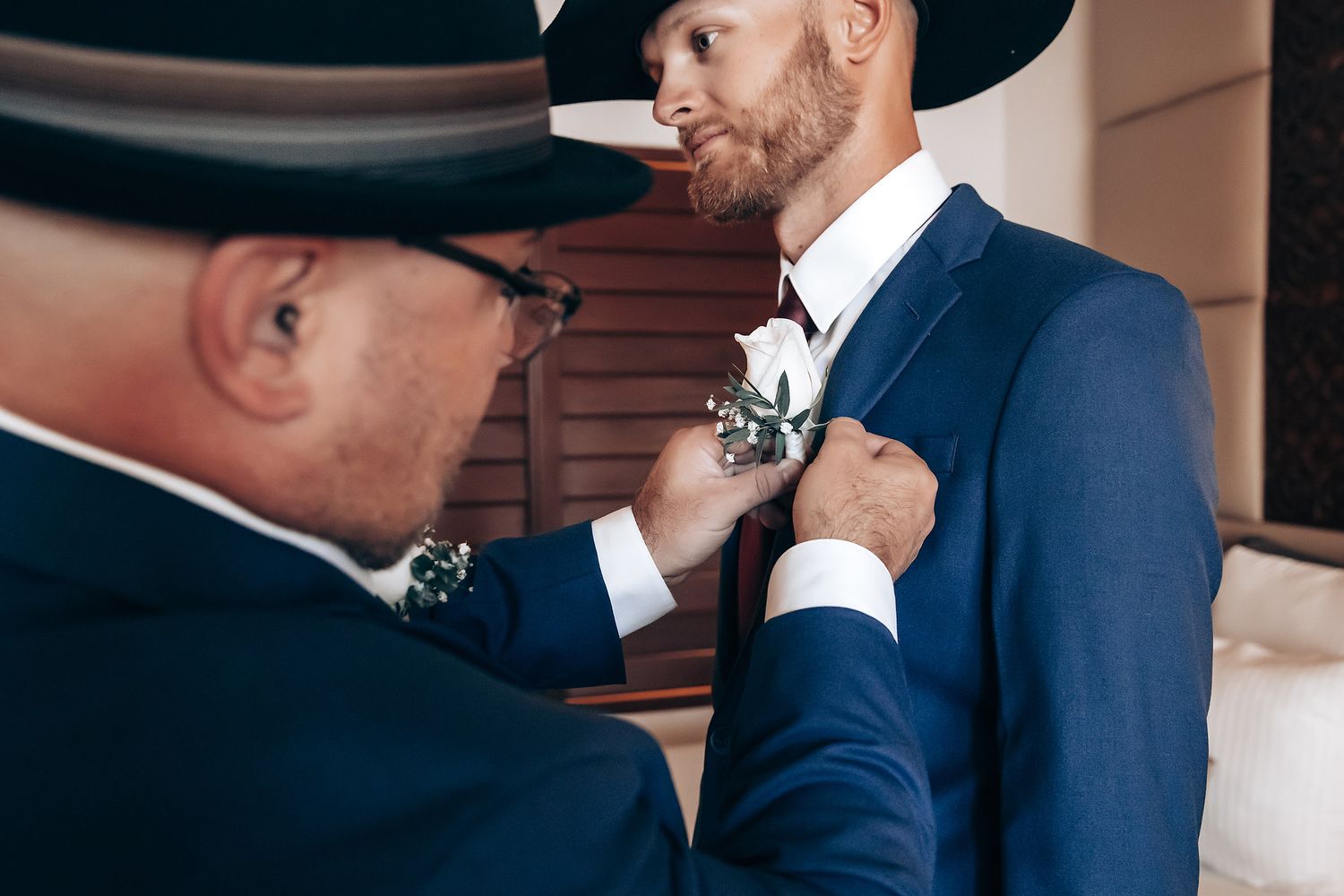 A man in a suit being assisted by another man, likely a groomsman, at a wedding ceremony.
