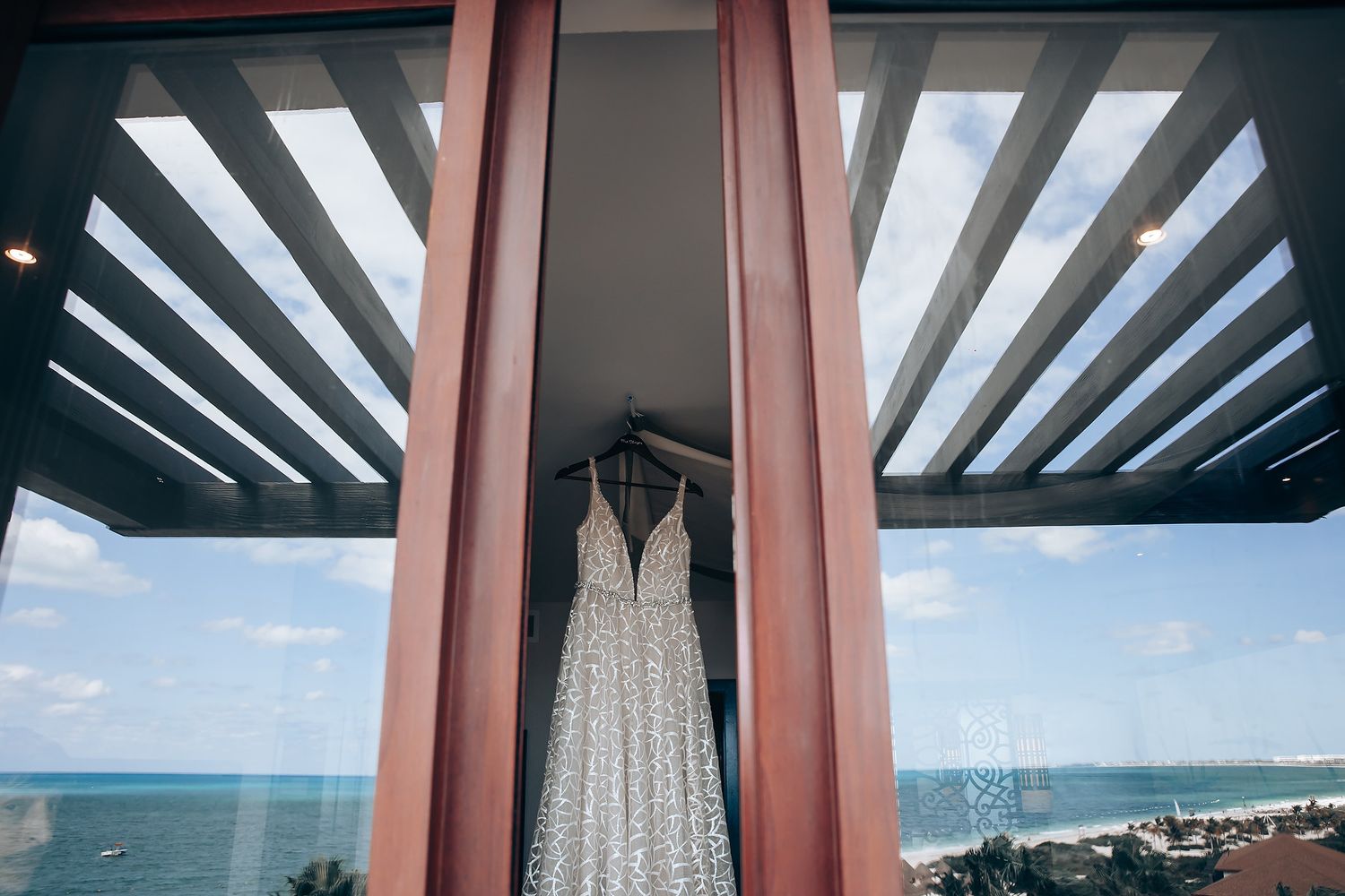 A modern architectural structure with intersecting beams and a view of the ocean in the background.