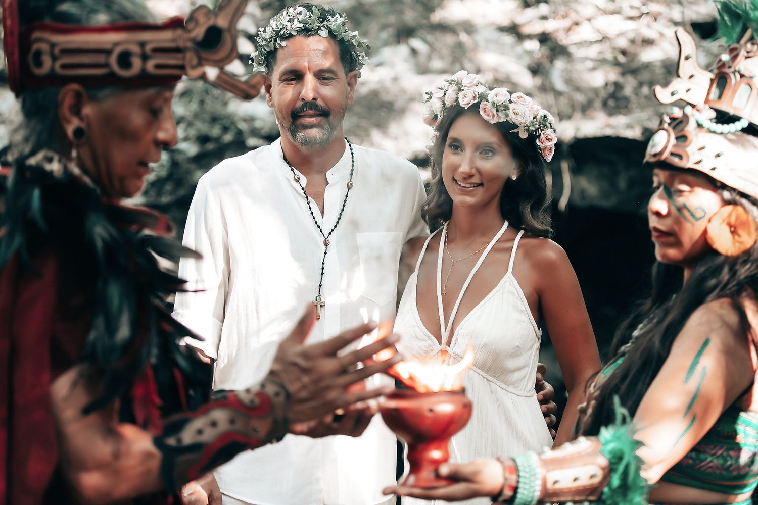 A couple embracing and smiling at each other during what appears to be a wedding or celebration in an outdoor, natural environment.