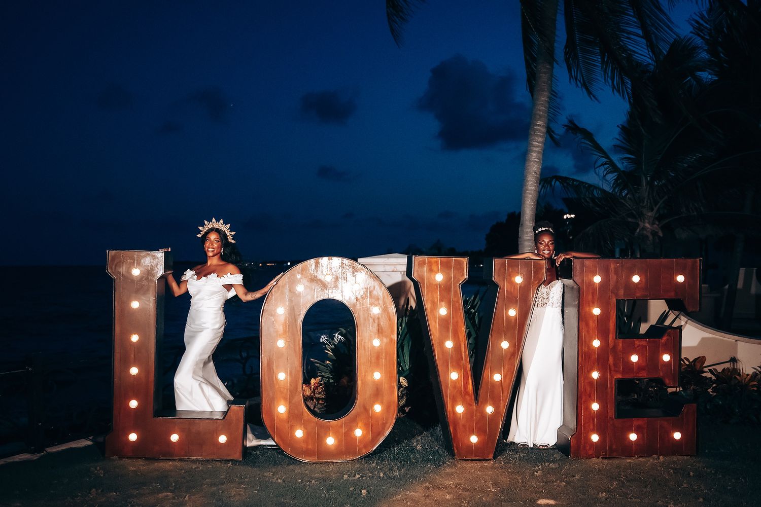 Illuminated LOVE sign creates romantic backdrop for evening wedding photos.