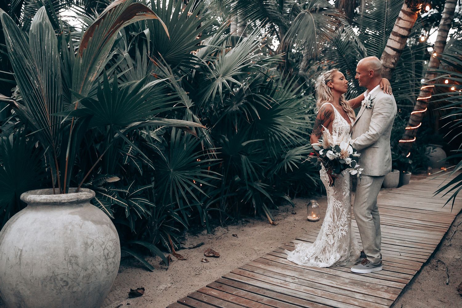 A wedding celebration moment on a wooden walkway surrounded by tropical garden landscaping.