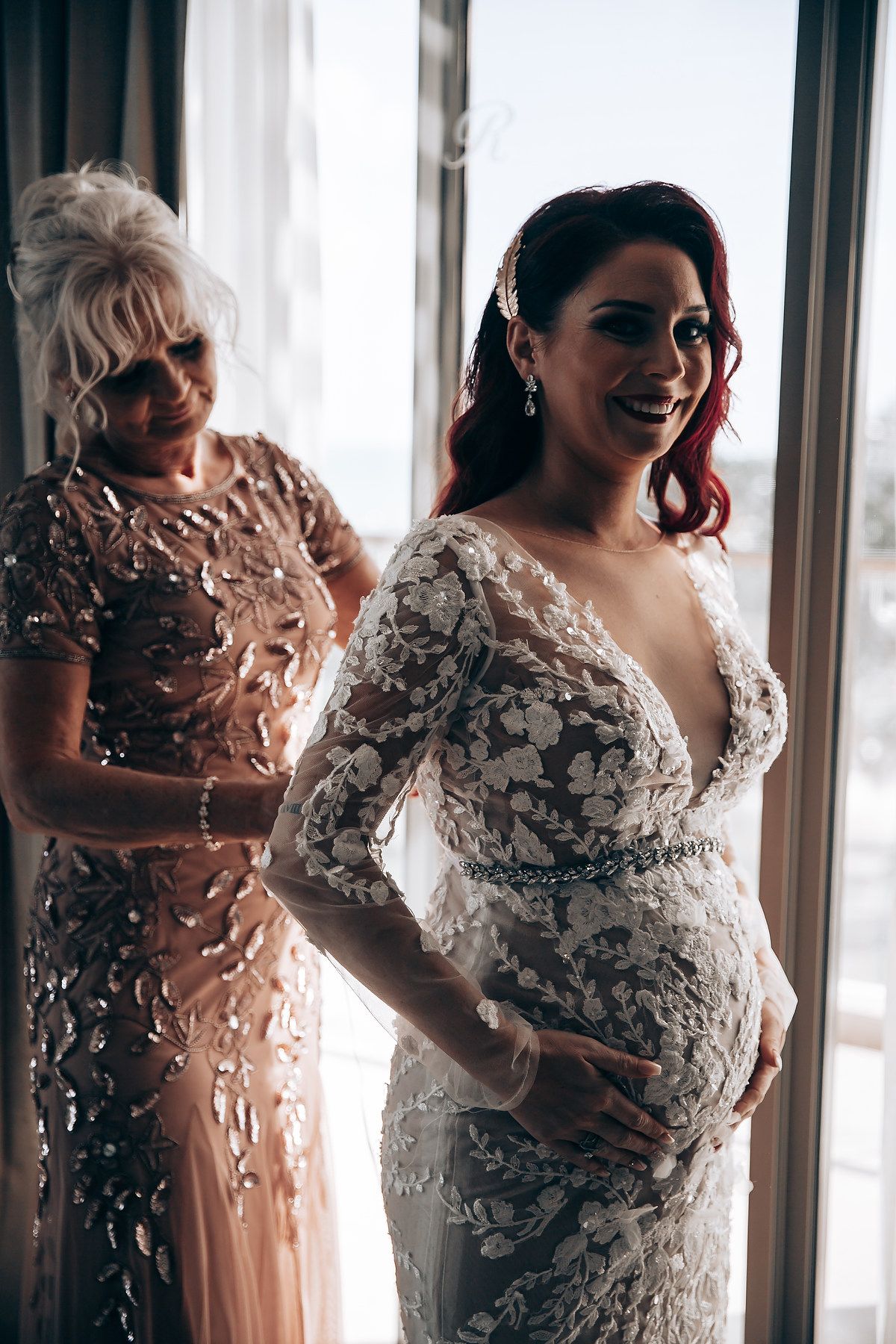 Elegant white wedding dress with intricate lace and floral appliques captured in natural window light.