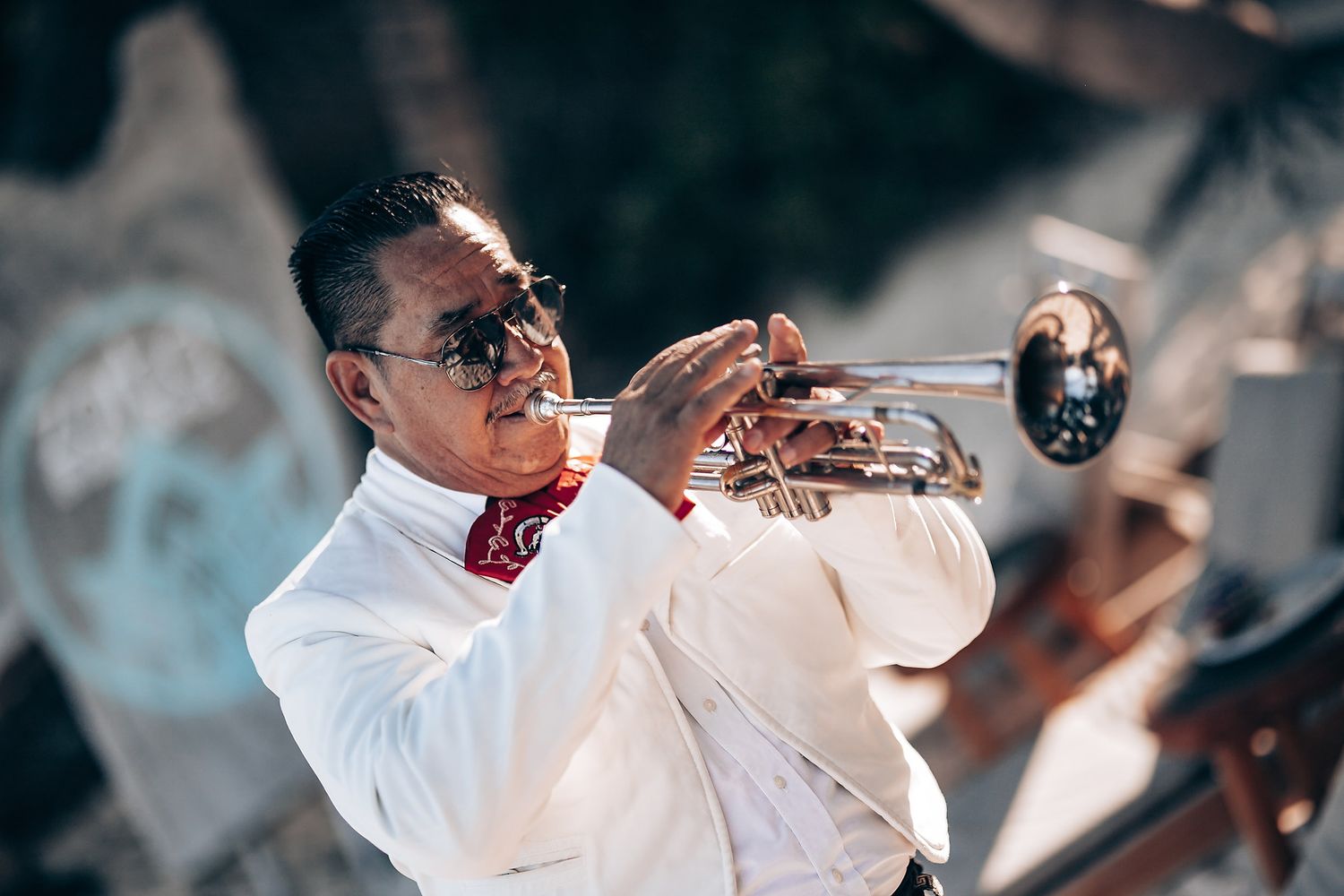Musicians in white attire perform live music at an outdoor celebration.