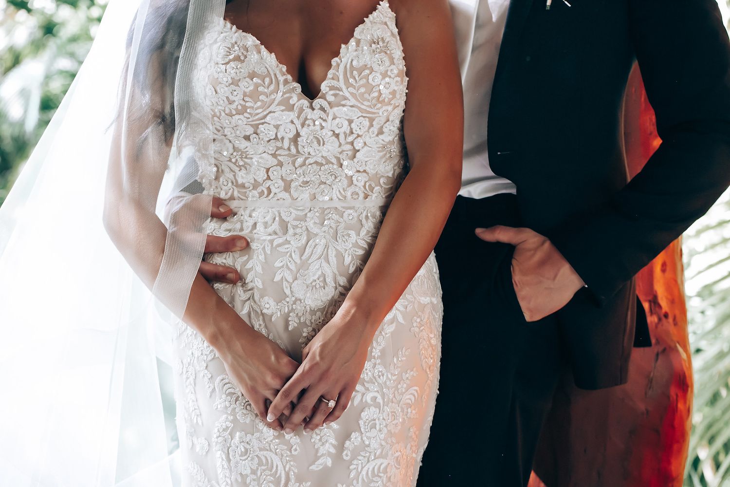 Elegant lace wedding dress details shown during outdoor ceremony.