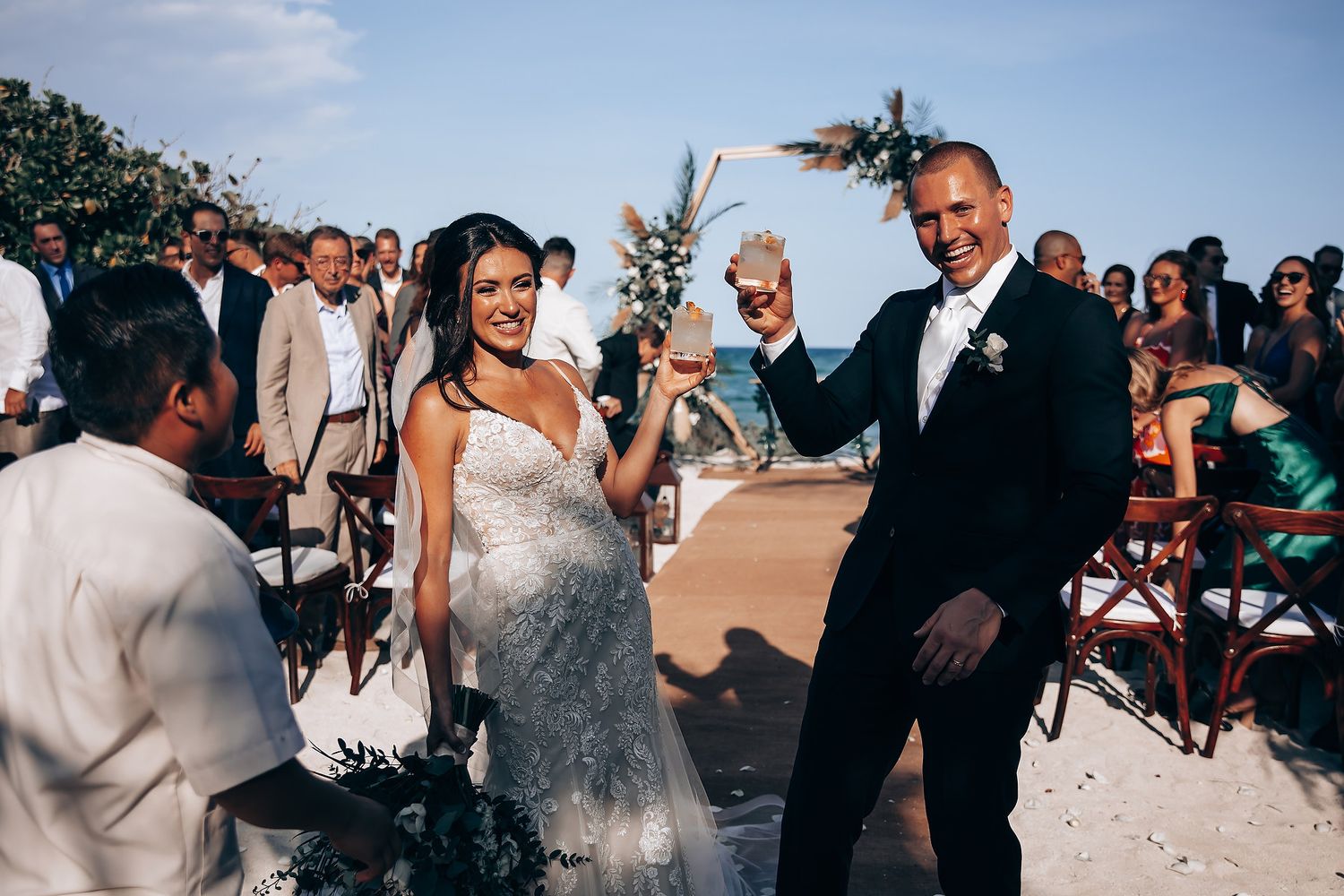 Wedding celebration with confetti toss on a sunny beach.