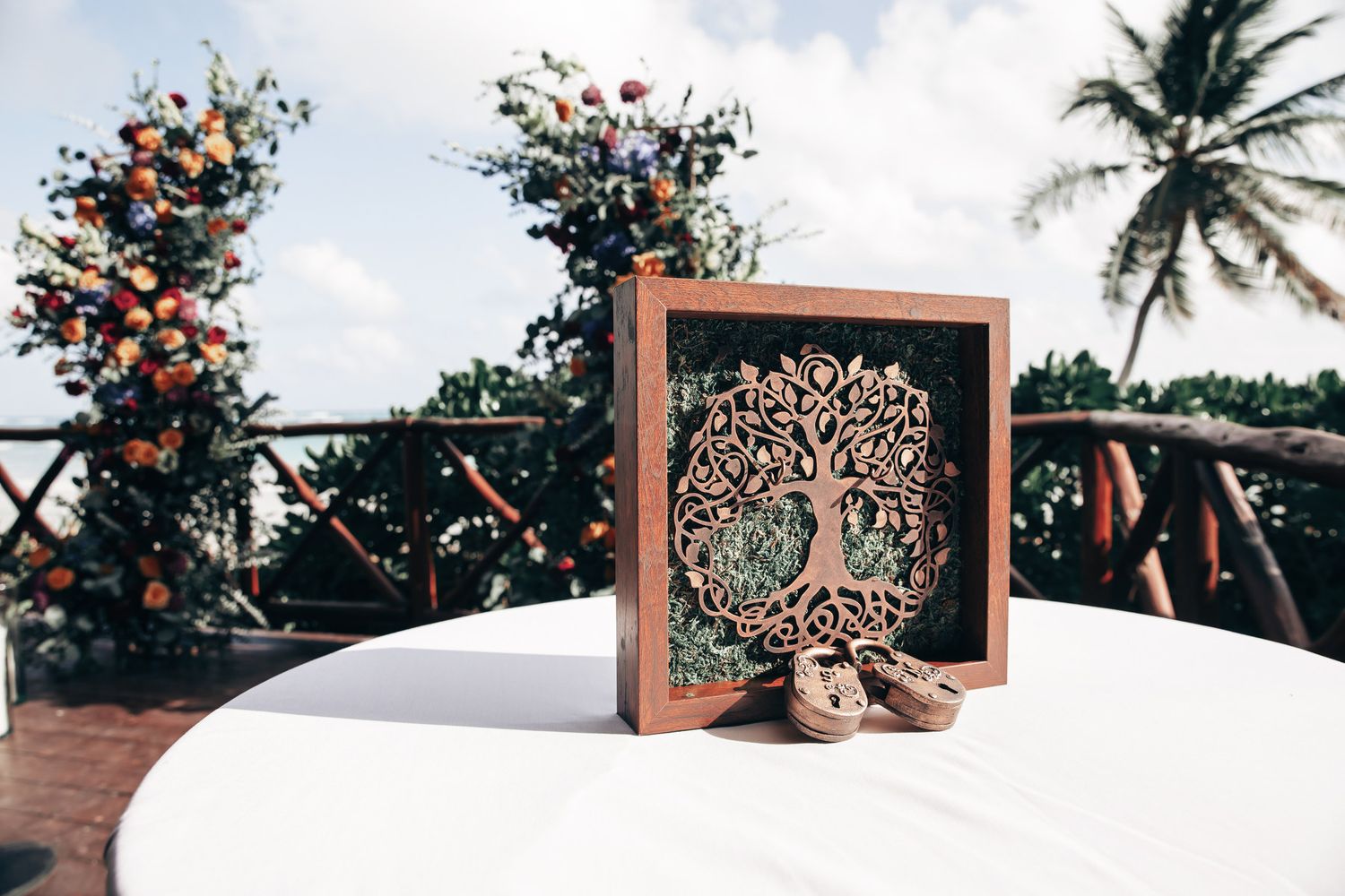 Decorative wooden tree of life shadow box centerpiece at tropical beach wedding reception.
