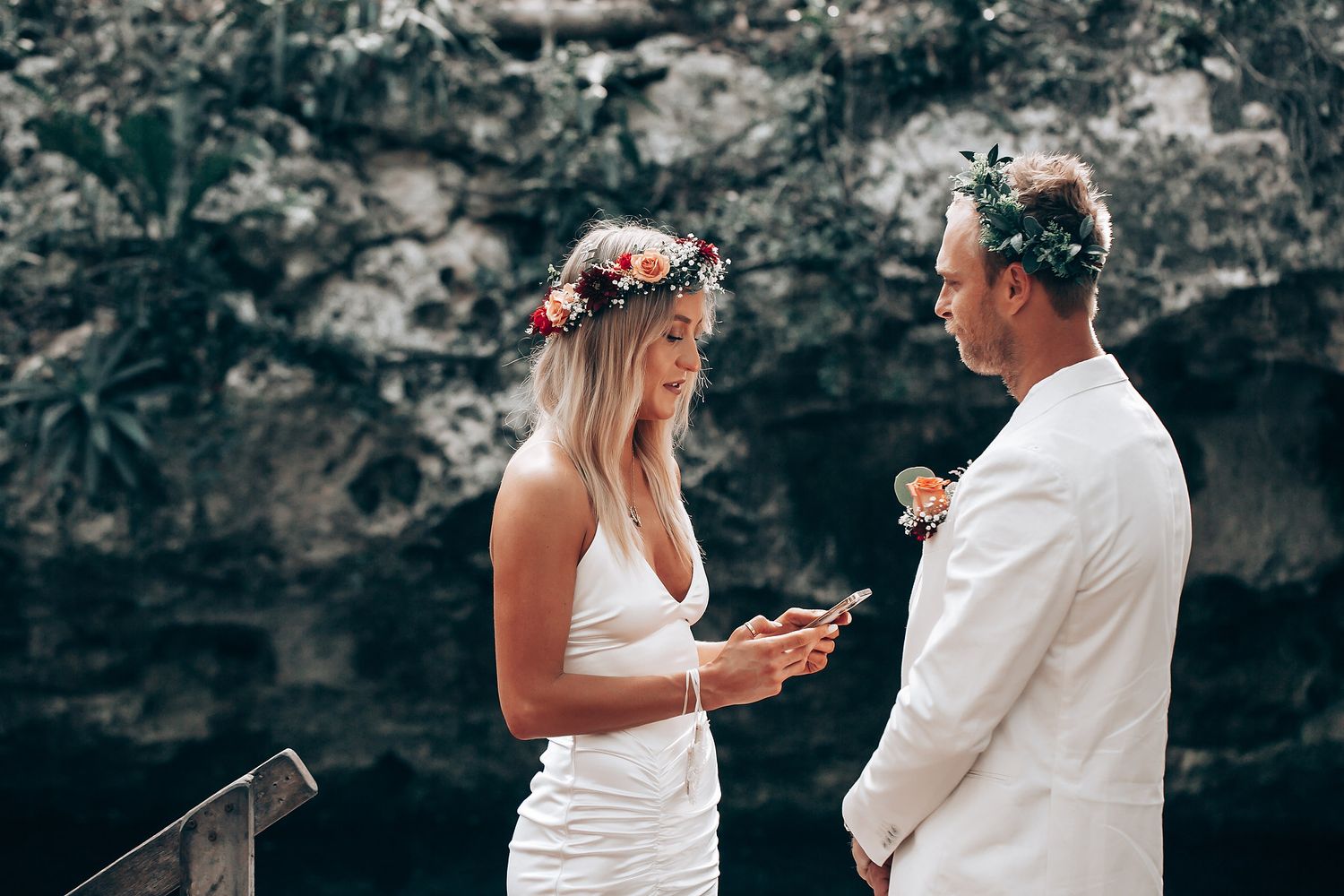 Intimate outdoor celebration scene with white attire and natural forest backdrop.