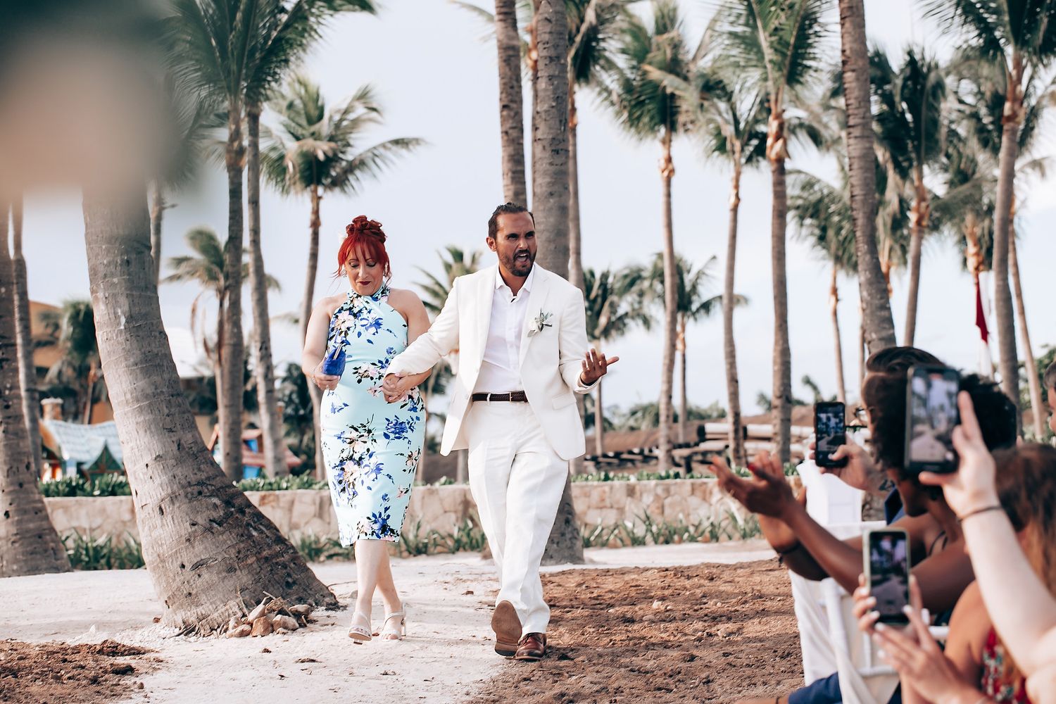 Palm trees line a tropical beach pathway on a sunny wedding day.
