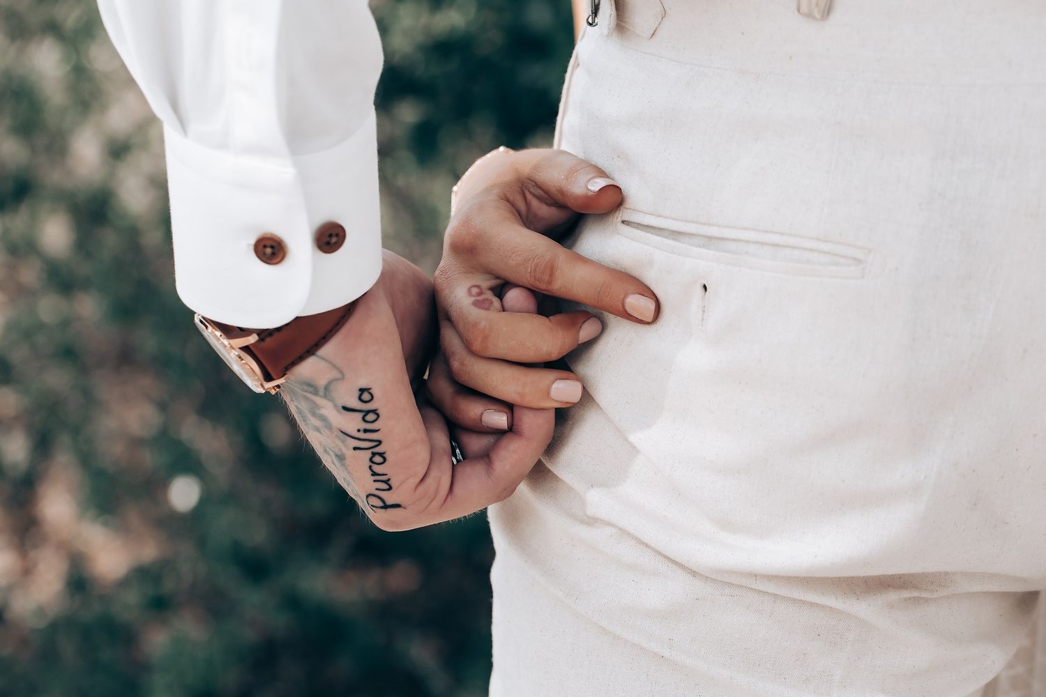 Close-up details of white wedding attire and hands during an intimate moment.