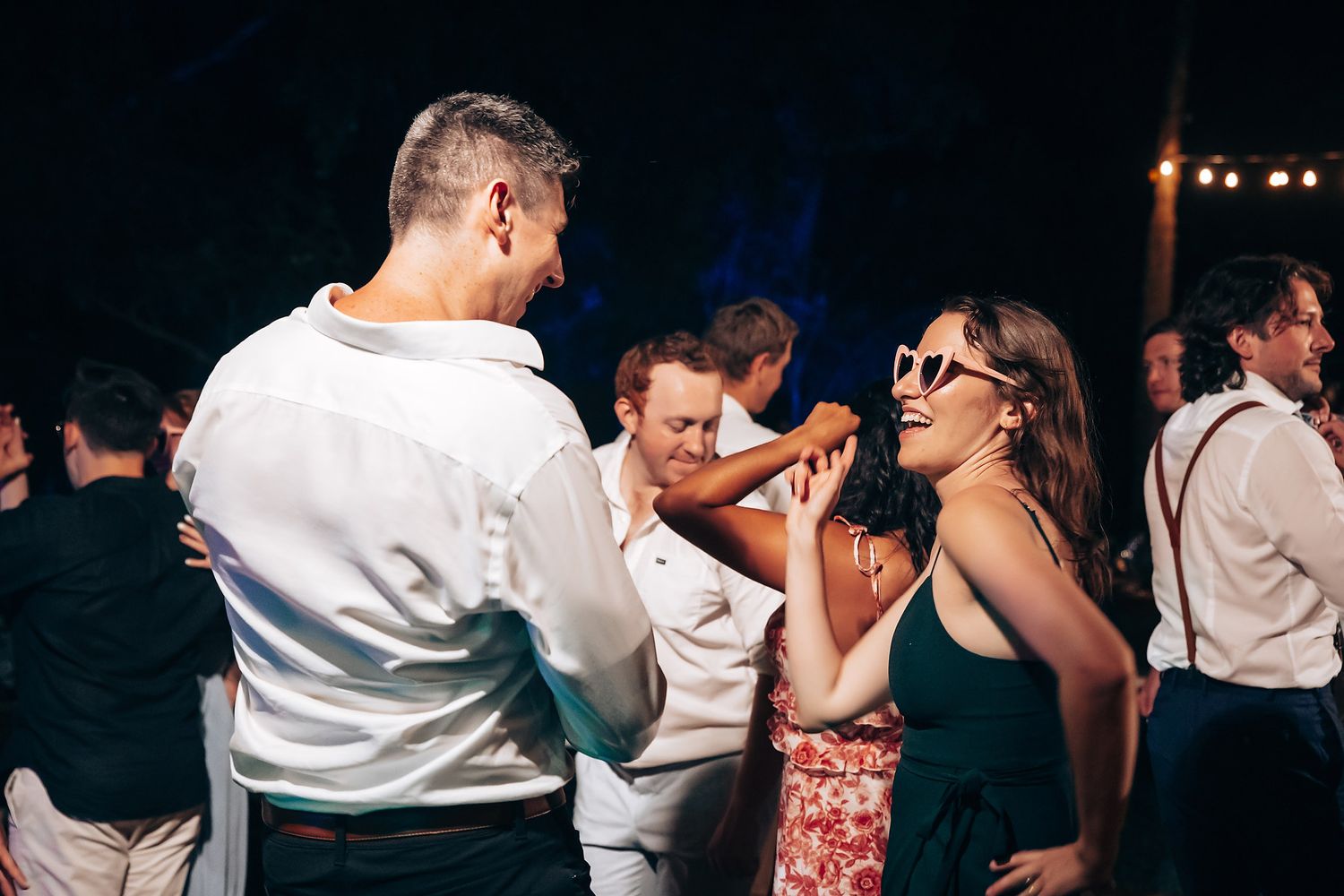 Couples dance together on a dimly lit dance floor during a romantic evening celebration.
