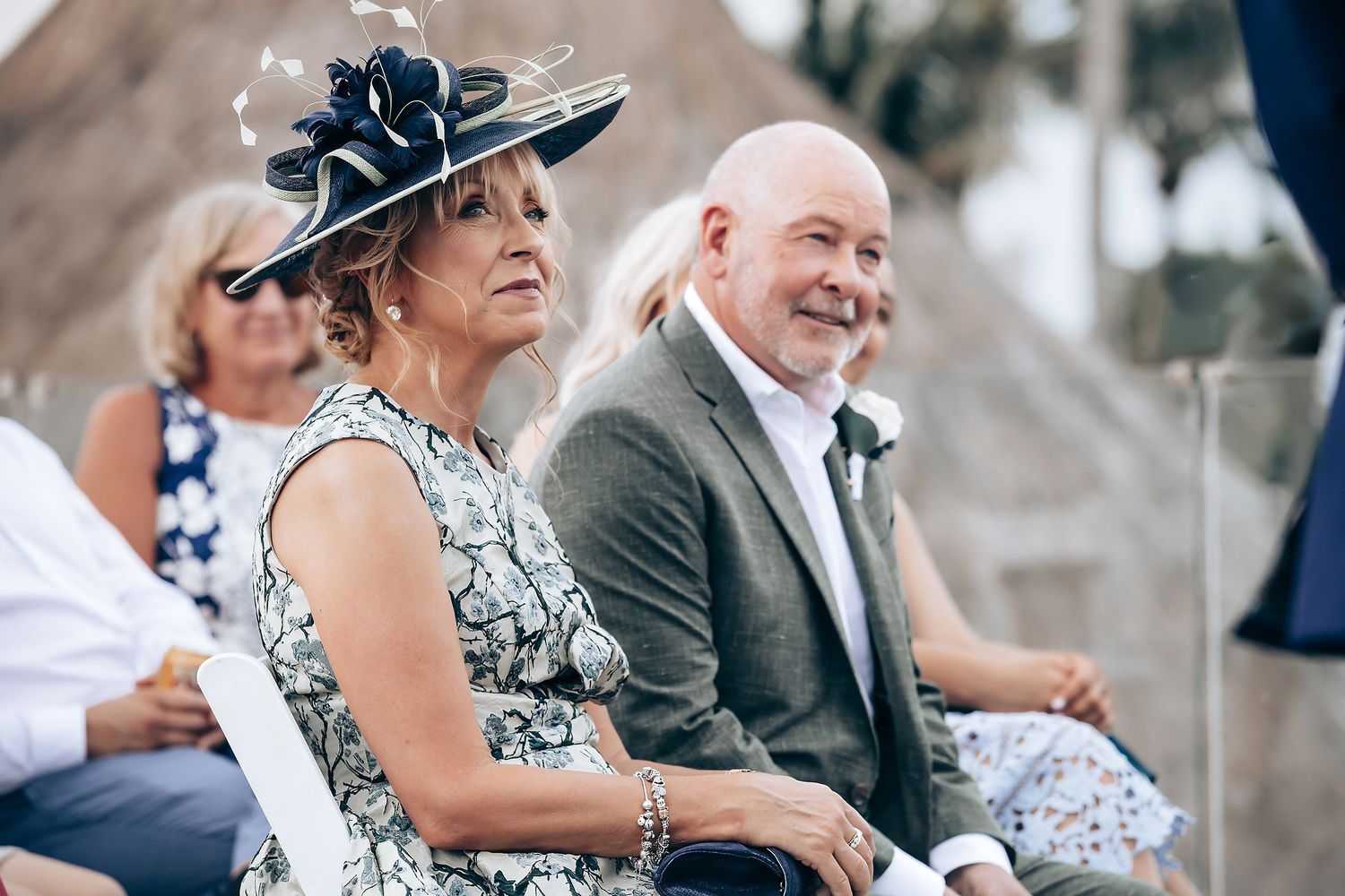 Wedding guests seated outdoors enjoying a beachside ceremony.