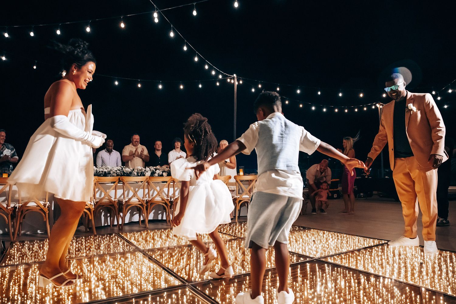Evening beach celebration with string lights illuminating the sandy setting.