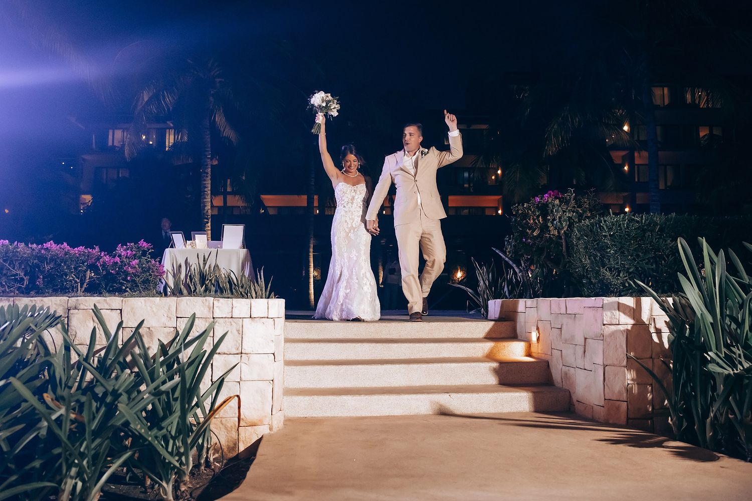 Evening wedding reception under string lights with guests seated at outdoor tables.