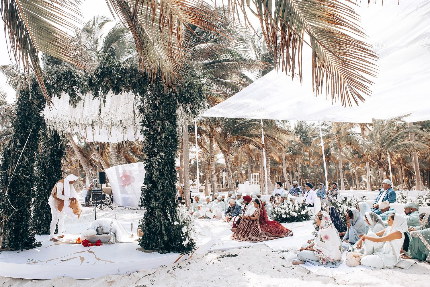 Coastal wedding ceremony location with natural palm fronds and white decor.