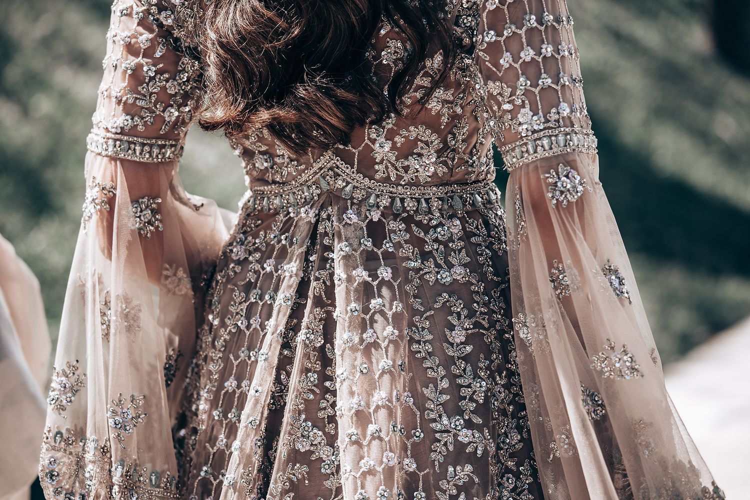 Close-up detail of intricate beadwork on a champagne-colored formal gown.