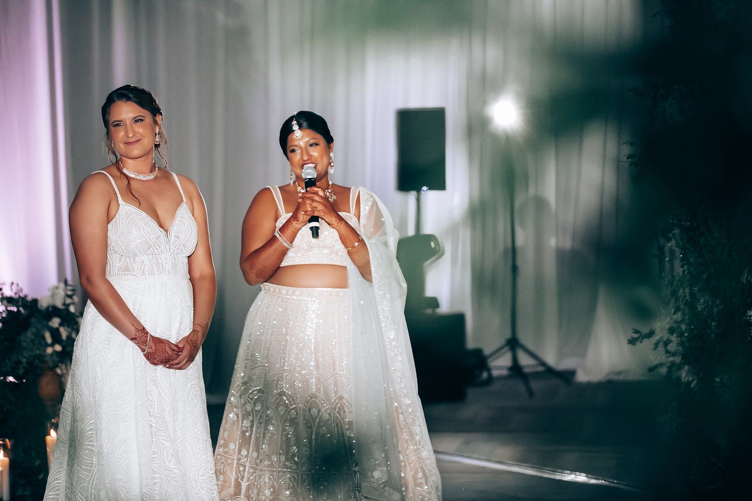 Wedding celebration captured in an elegant white-draped venue with modern lighting.
