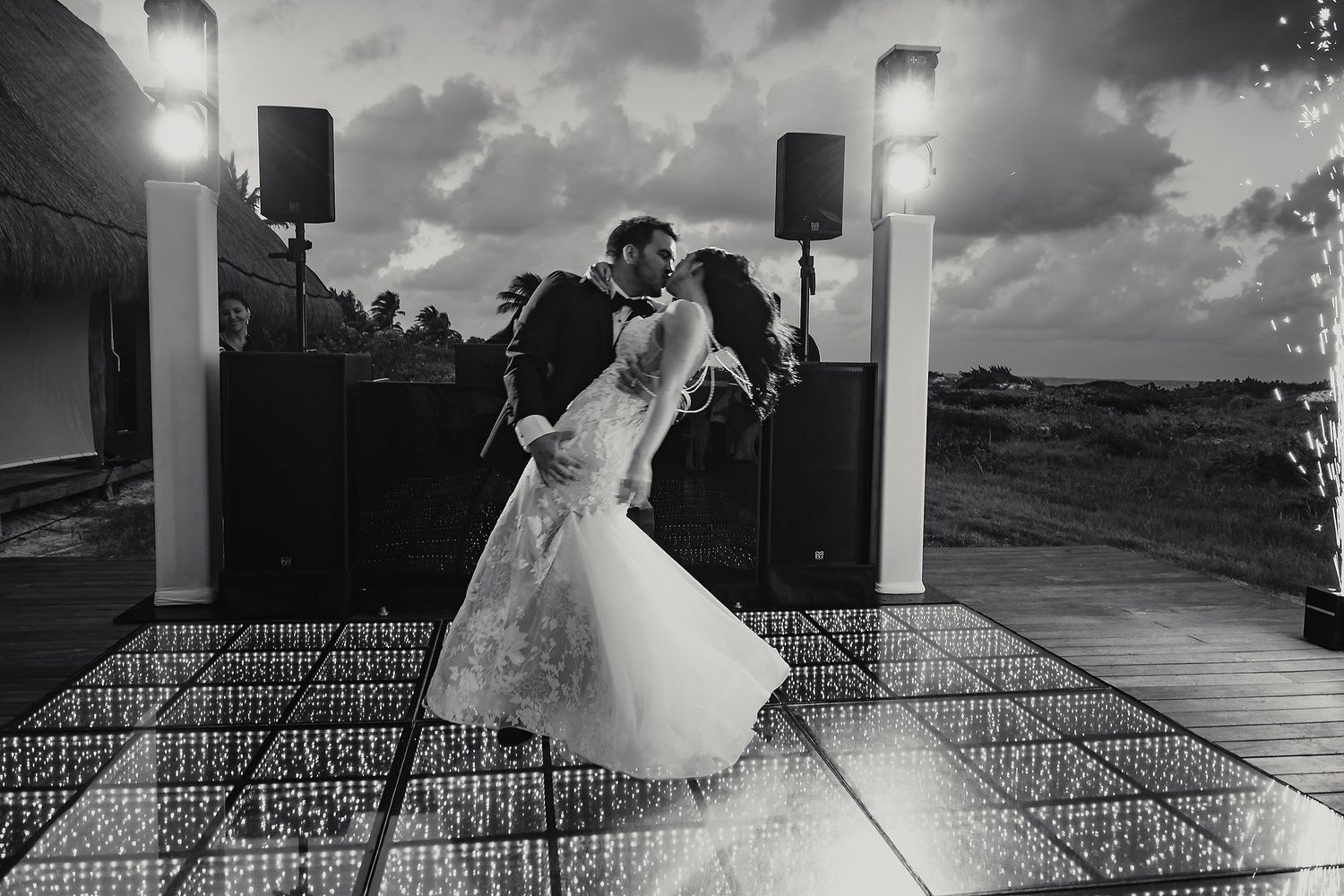 Black and white photo of an outdoor wedding ceremony setup with rows of chairs under cloudy skies.