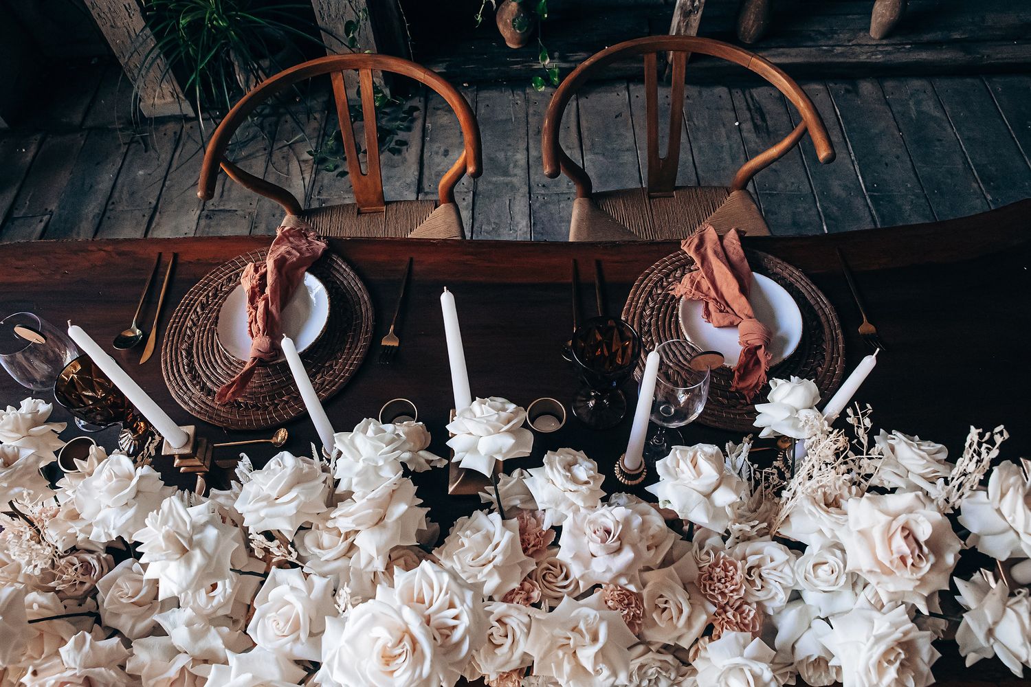 Rustic wooden table decorated with white floral arrangements and metallic accents for an elegant event.