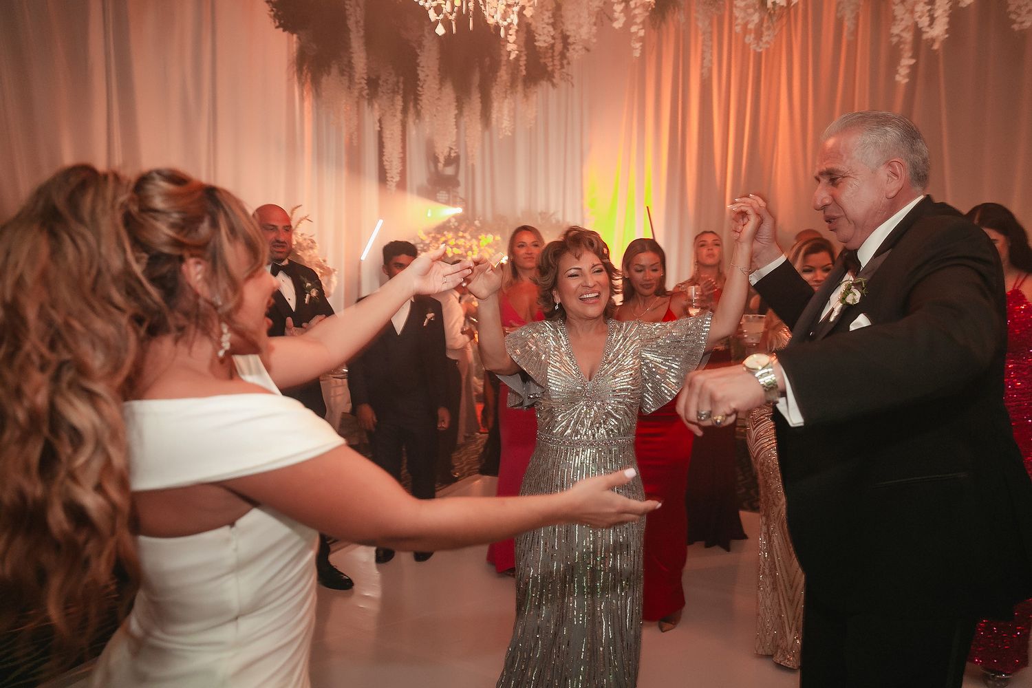 Wedding guests dance together on an illuminated ballroom floor during an elegant evening reception.