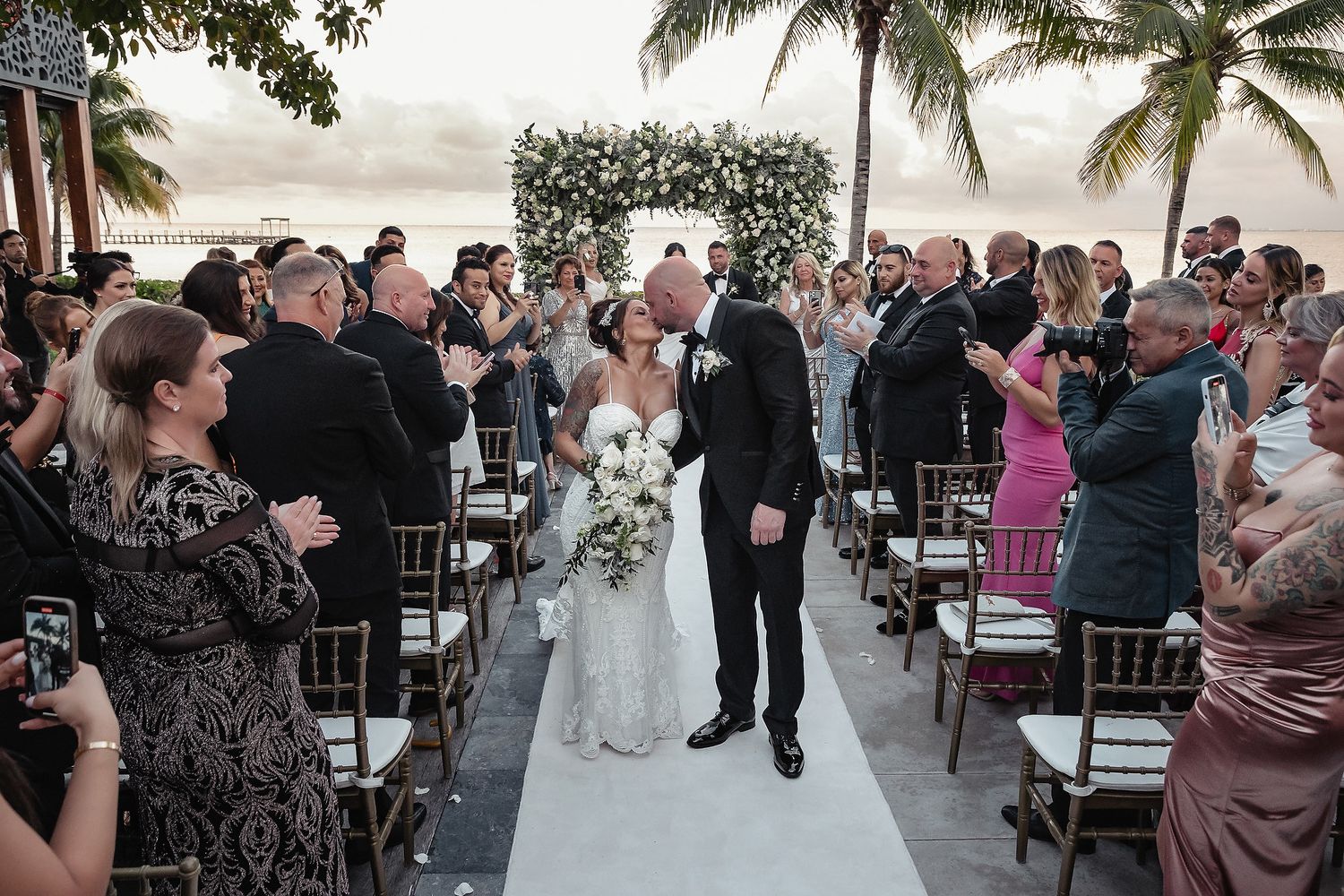 Outdoor wedding ceremony setup with palm trees and ocean views at a tropical beach resort.