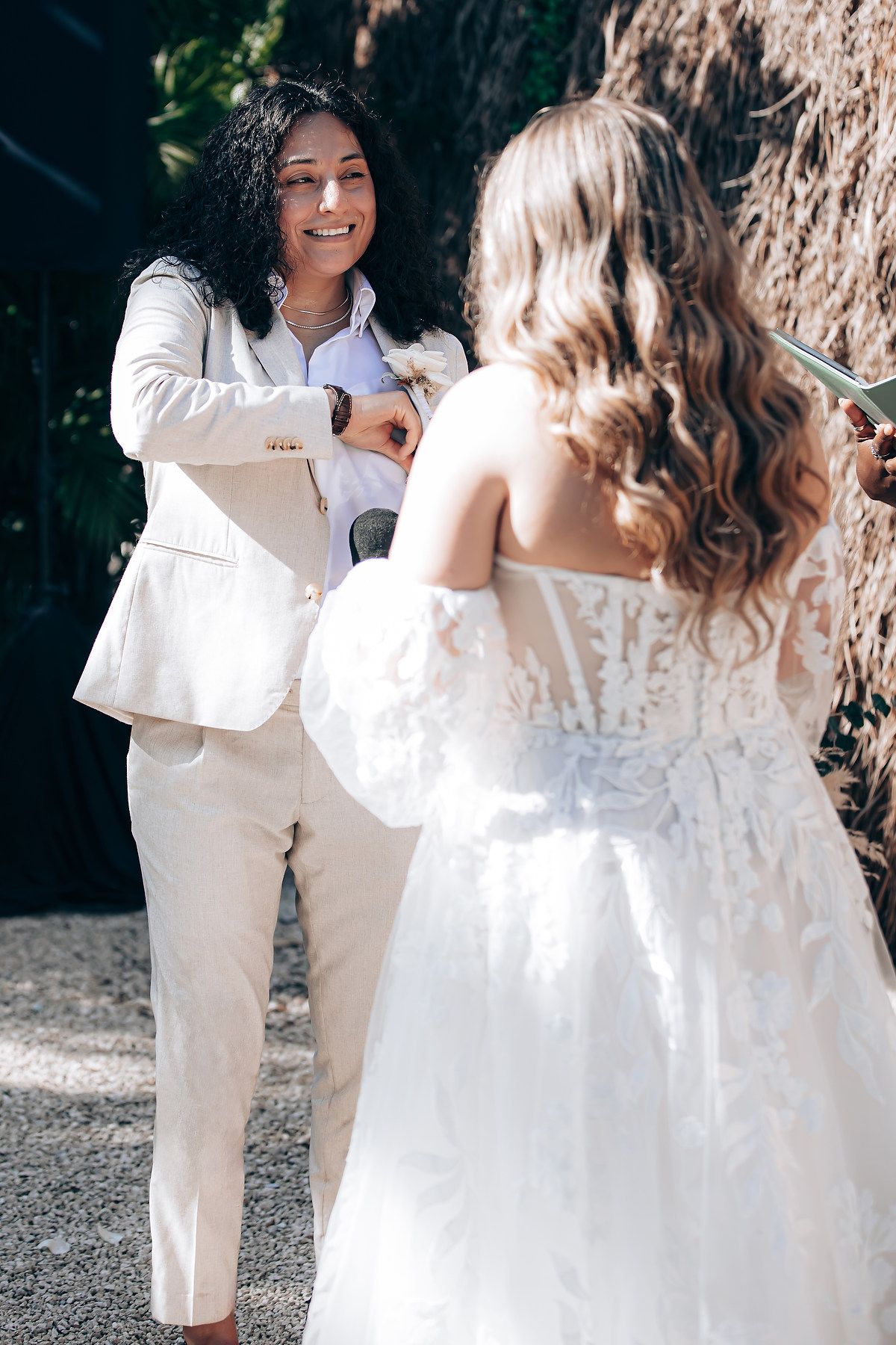 A couple shares an intimate moment during their wedding celebration against a rustic backdrop.