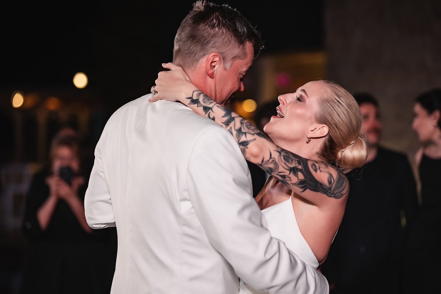 Couple shares their first dance on a black and white checkered floor at evening reception.