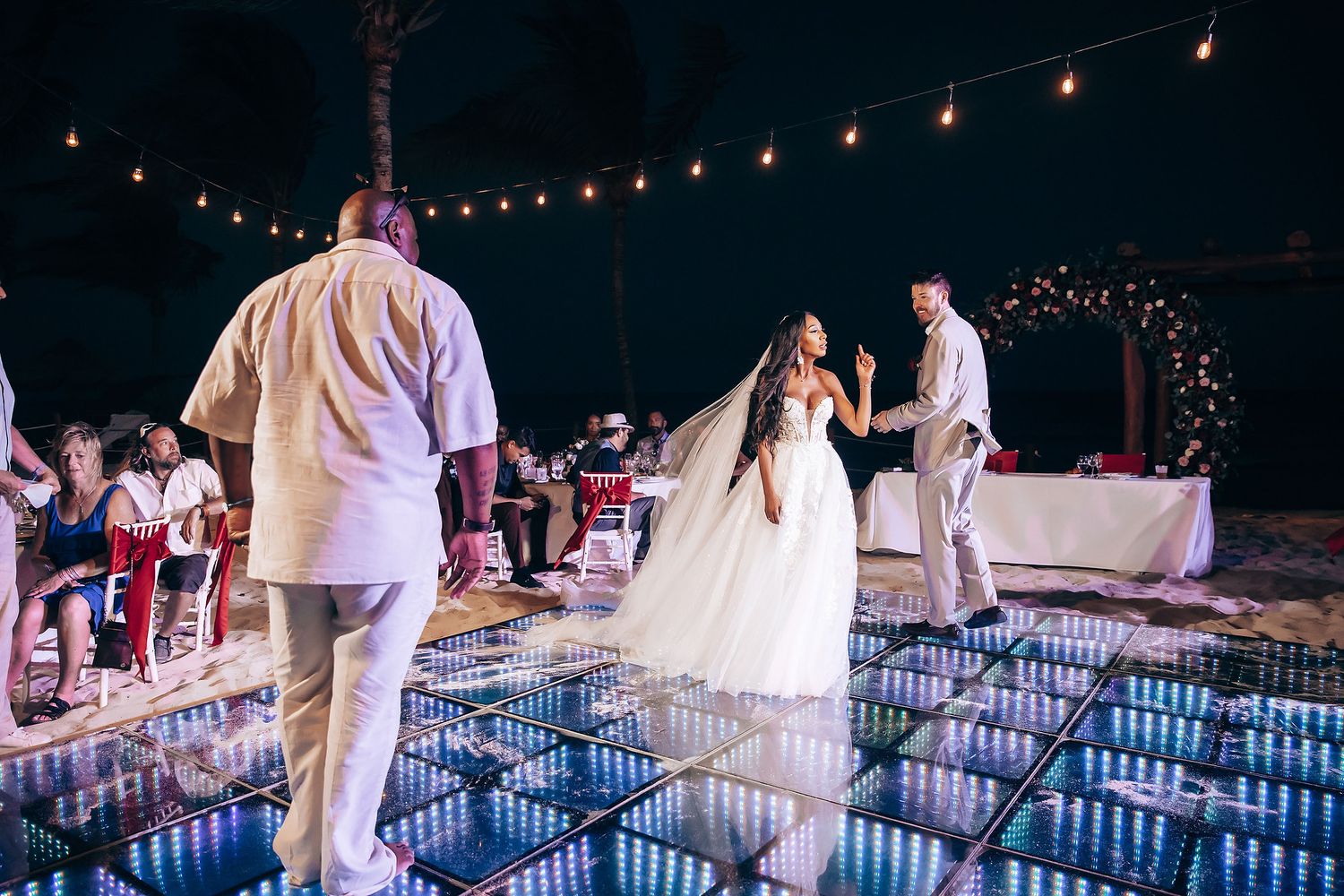 Evening wedding reception with string lights and guests dancing.