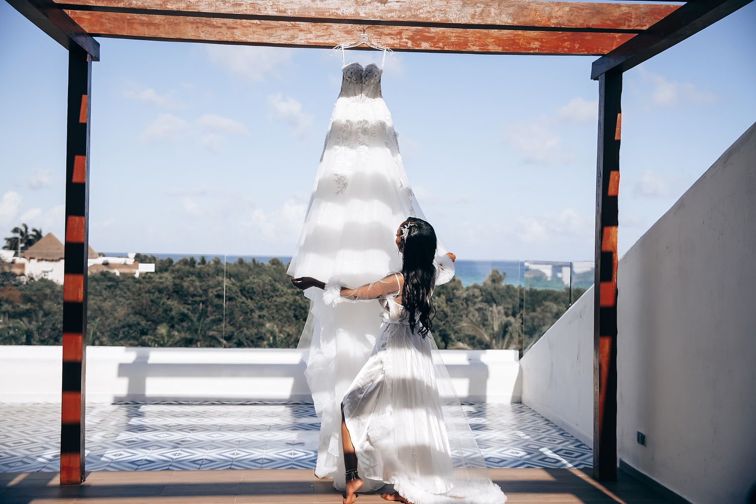 Scenic outdoor wedding ceremony setup with wooden beams and white draping overlooking mountains and ocean.