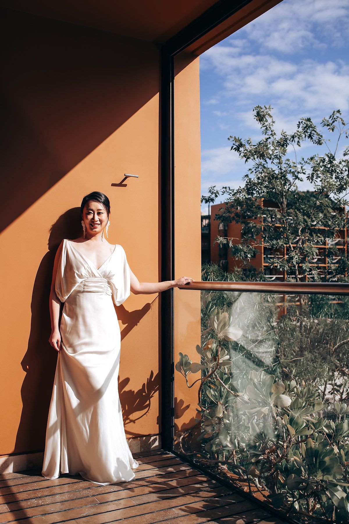 Sunlit terrace with orange walls featuring artistic bridal portraits in white.