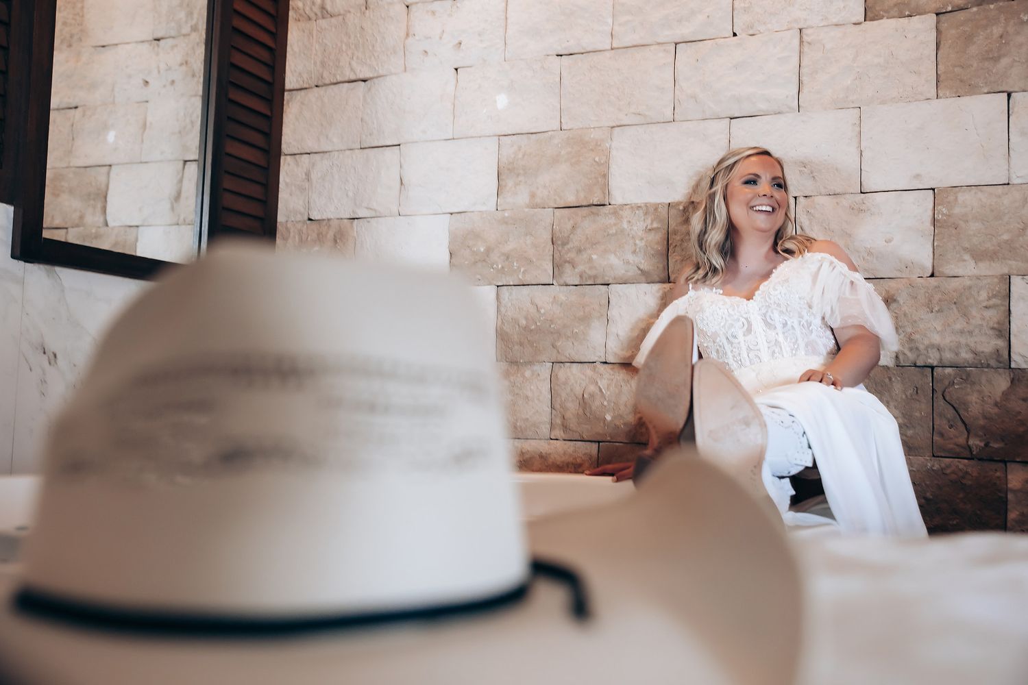 Bride seated against a rustic stone wall background in an intimate setting.