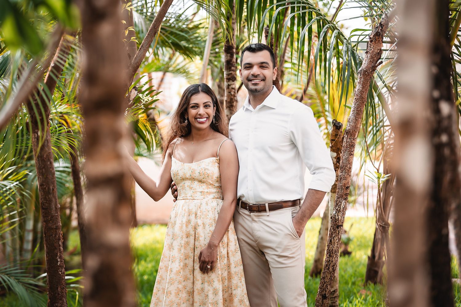 Candid moments captured of a couple in white and beige attire surrounded by tropical foliage.