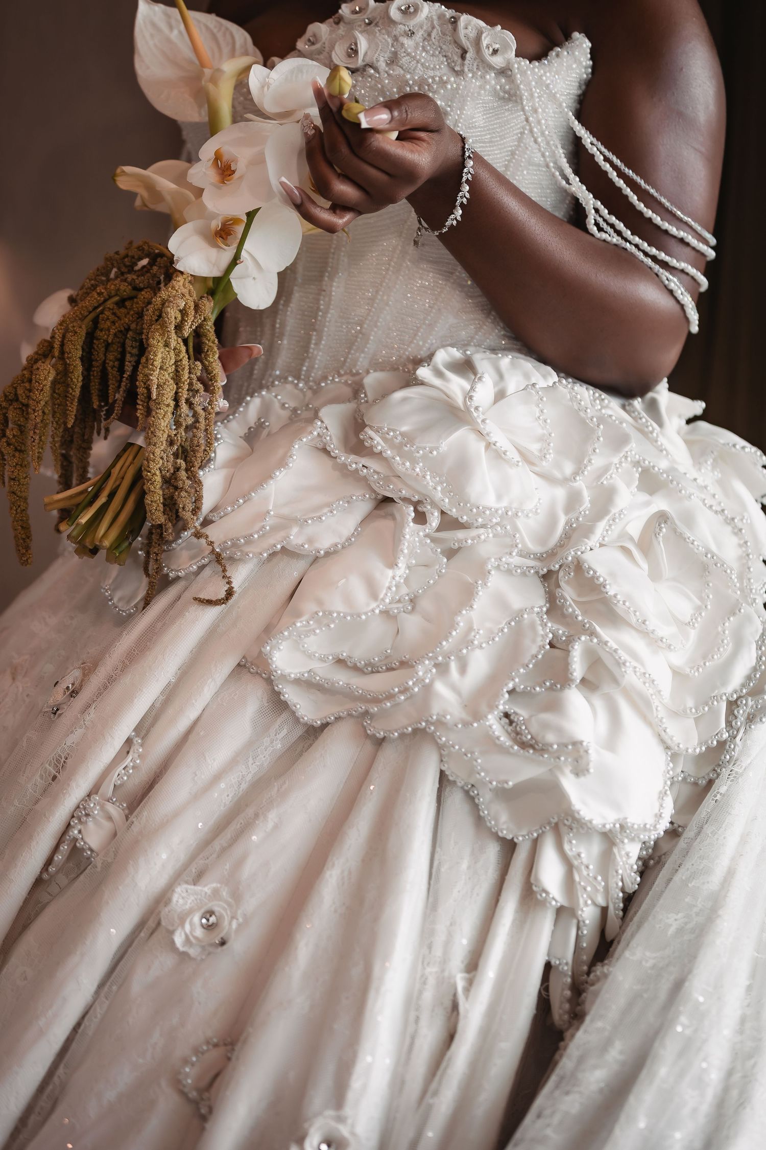 Close-up details of a luxurious white wedding dress with floral embellishments and lace.