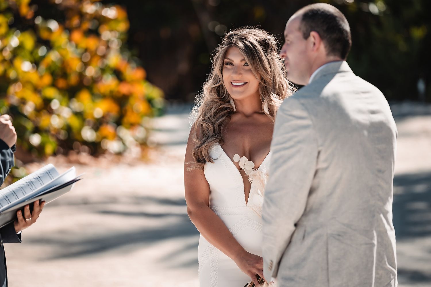A couple shares a joyful moment under autumn foliage at an outdoor wedding ceremony.