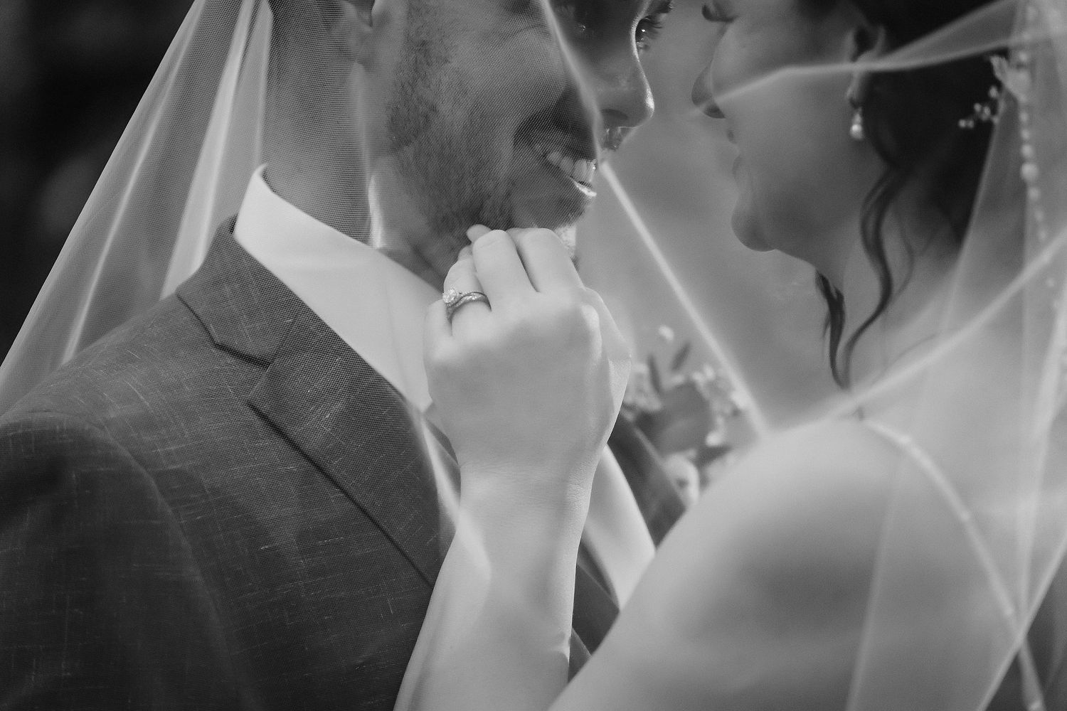 A romantic wedding ceremony moment captured in black and white on a beach with palm trees.