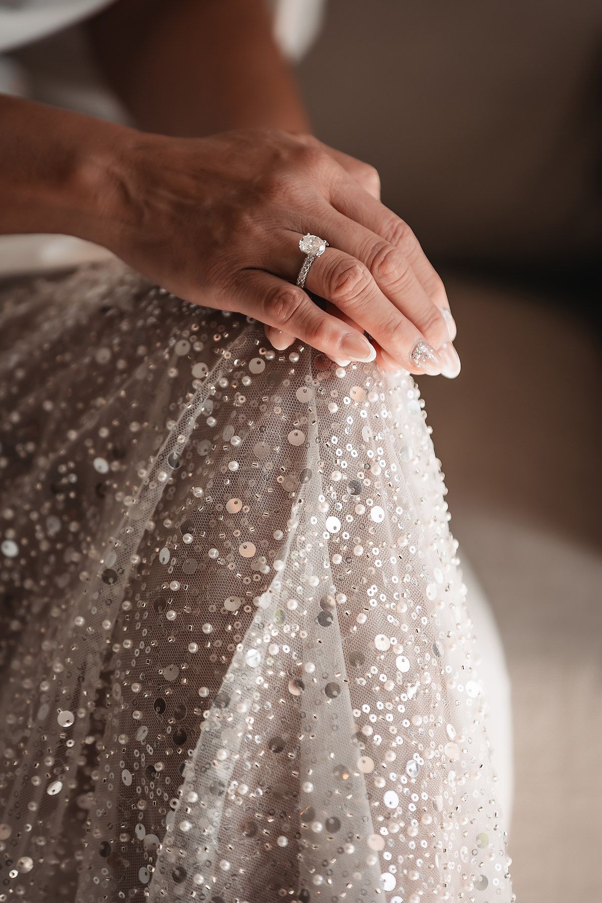 Close-up details of a wedding dress with intricate sequin and beaded embellishments creating a sparkling texture.
