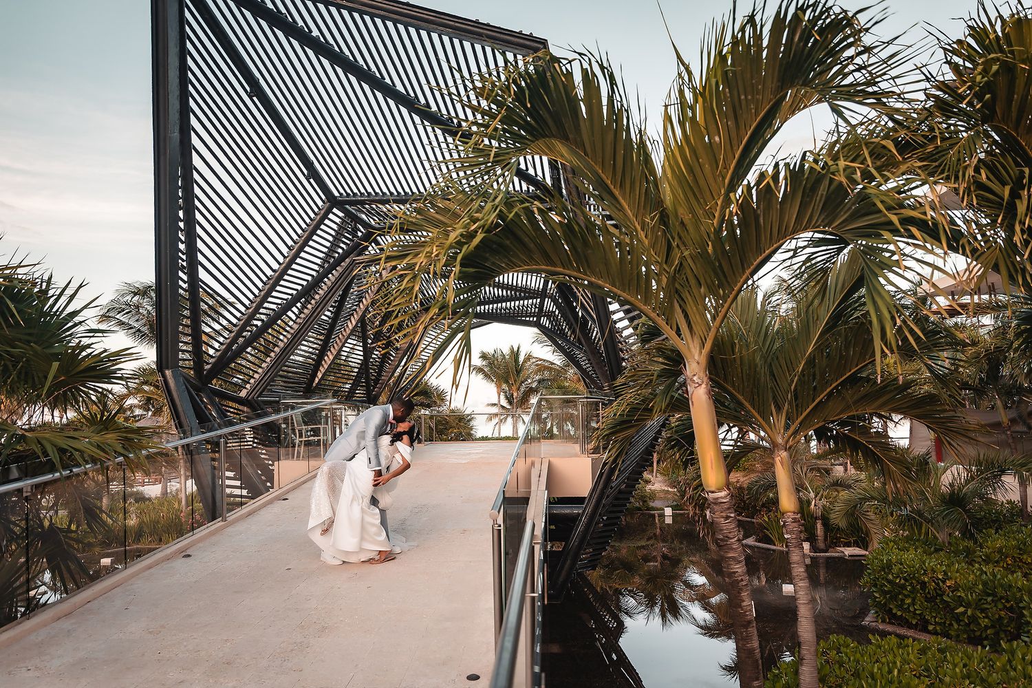 Scenic walkway with palm trees and modern architectural details at a beachfront wedding location.