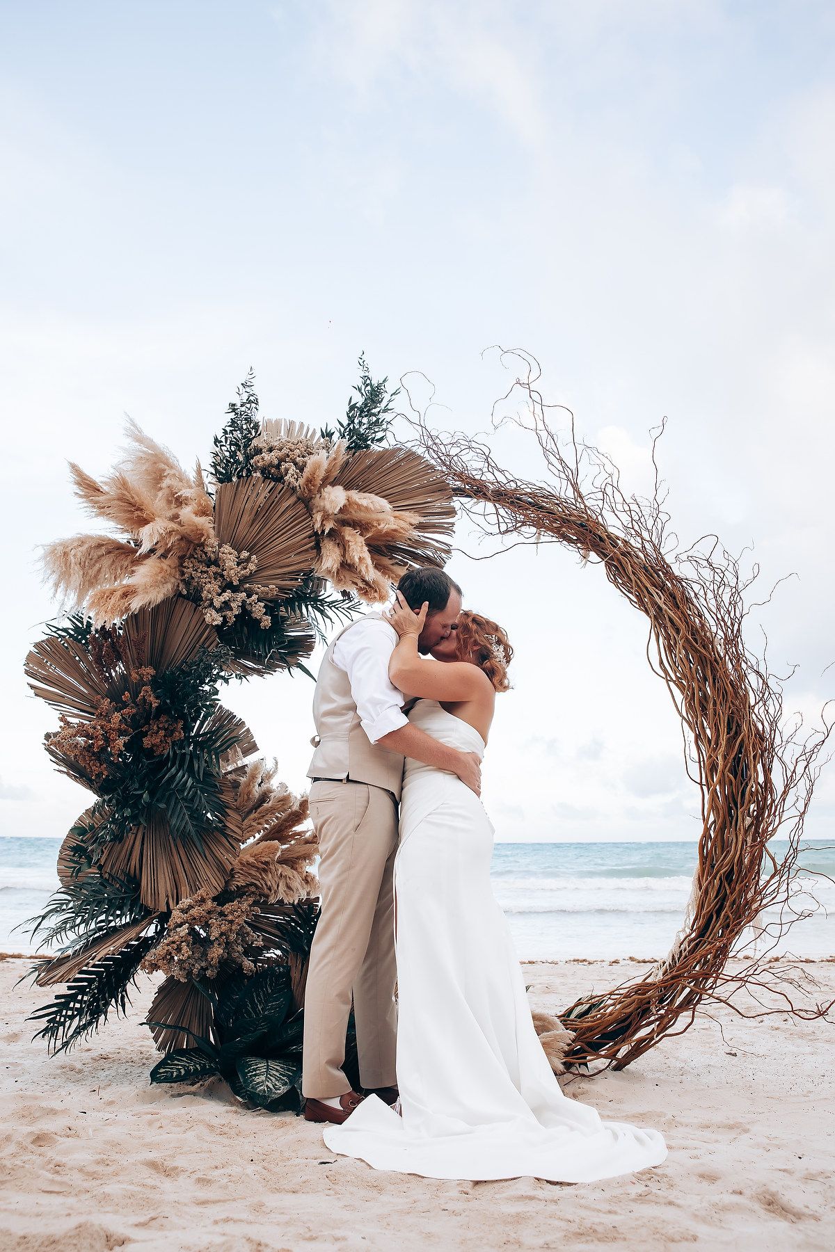 Romantic beach wedding scene with natural boho floral arrangements and ocean views.