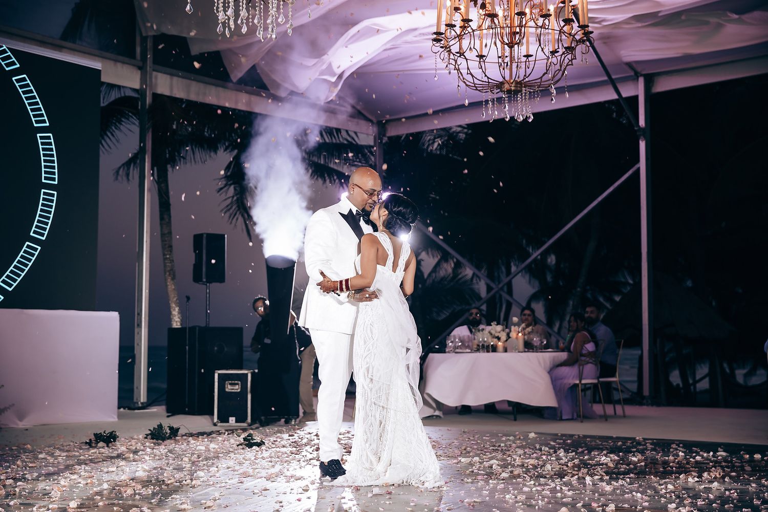 Wedding reception venue with dramatic purple lighting and elegant chandeliers creating an intimate atmosphere.