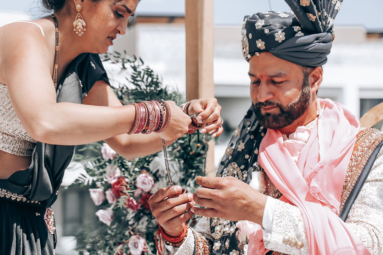 Traditional Indian wedding ceremony ritual with pink and silver attire and floral decorations.