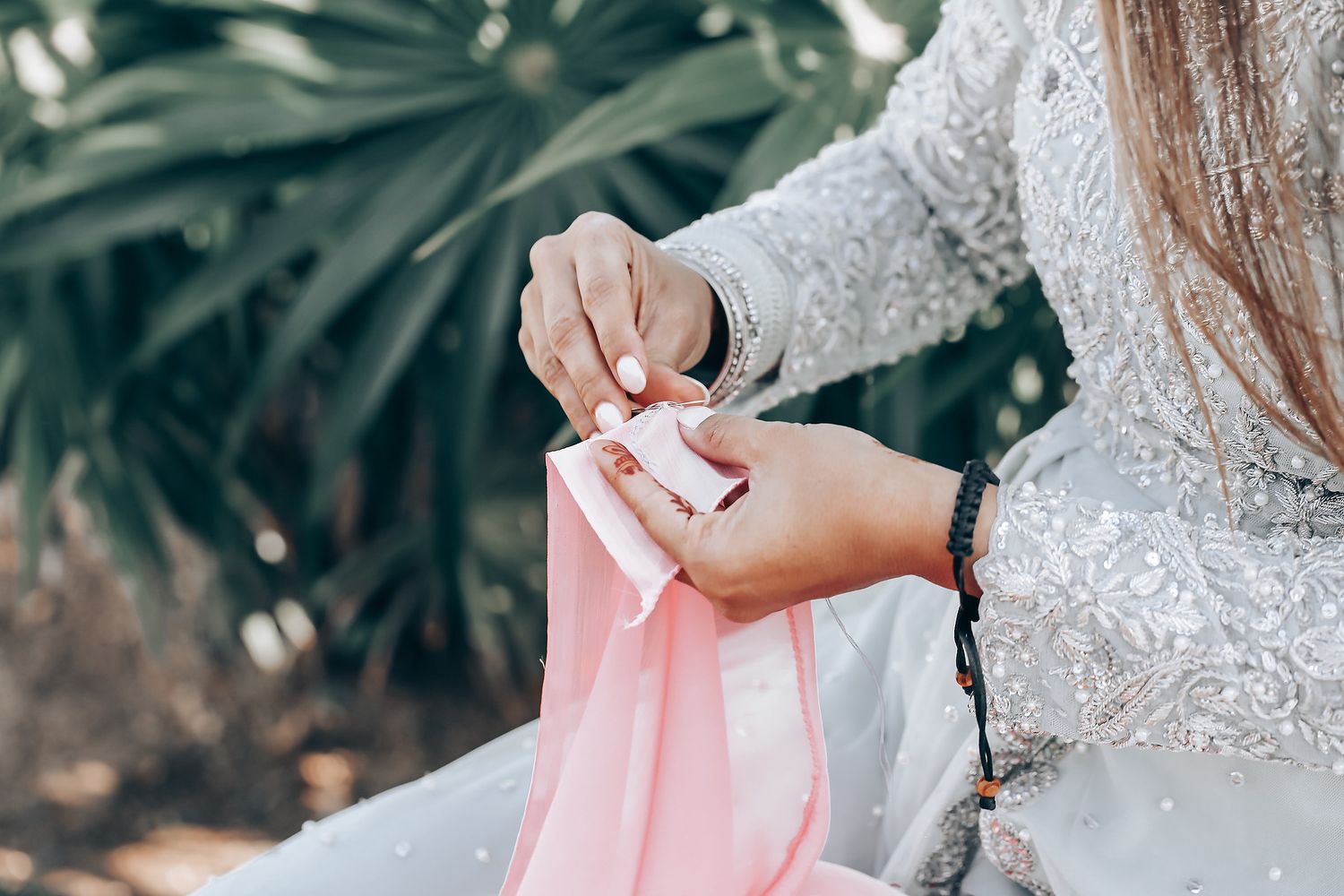 Close-up details of delicate white lace and pink fabric from formal attire.