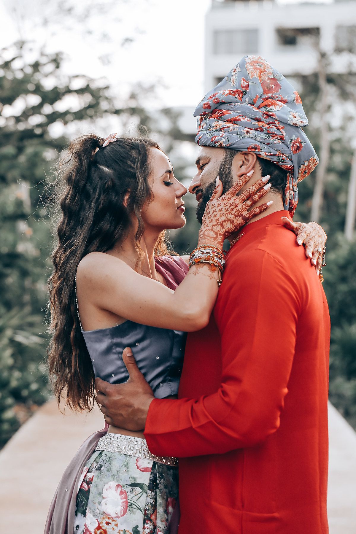 A couple in romantic embrace wearing red and gray clothing share tender moments in a series of outdoor photos.