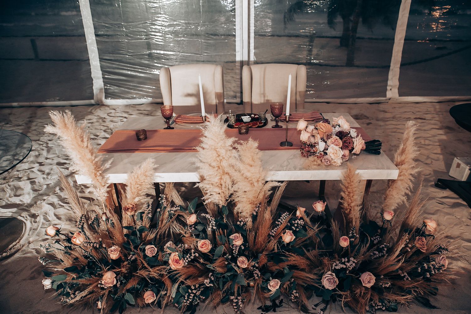 Romantic floral table centerpiece with white feathers and candles for wedding reception.