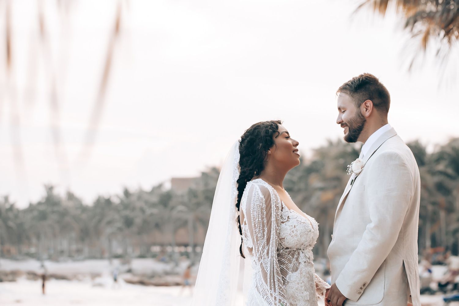 Ethereal beachside wedding portraits with flowing white dress and soft lighting at sunset.