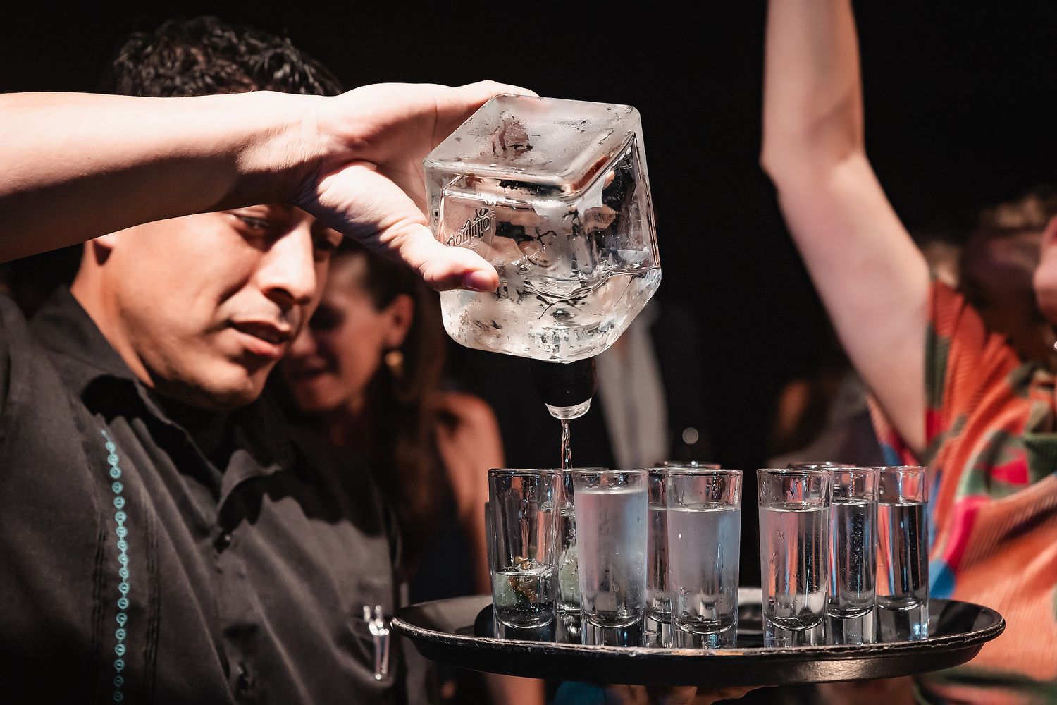 People dancing and celebrating at a lively nightclub party with drinks and energetic atmosphere.