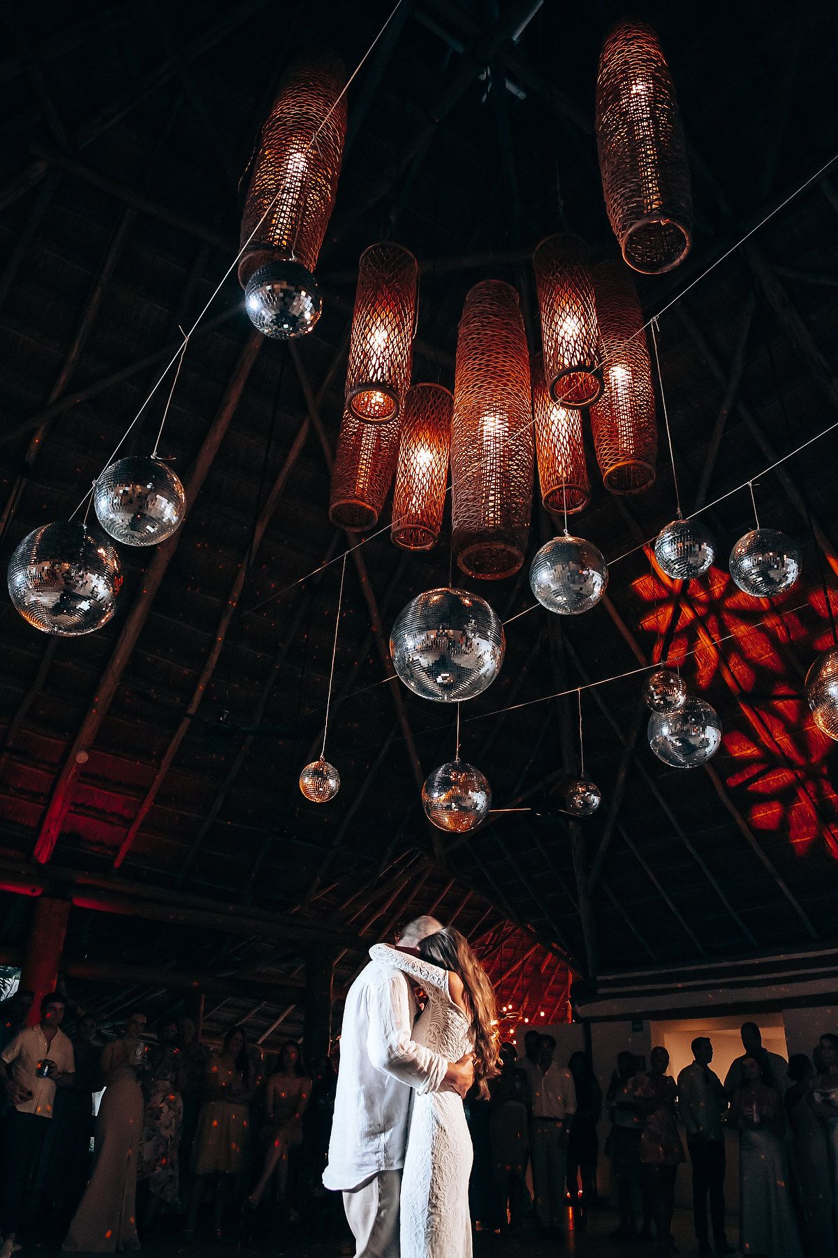 Romantic dance moment captured under hanging disco balls and copper lanterns.